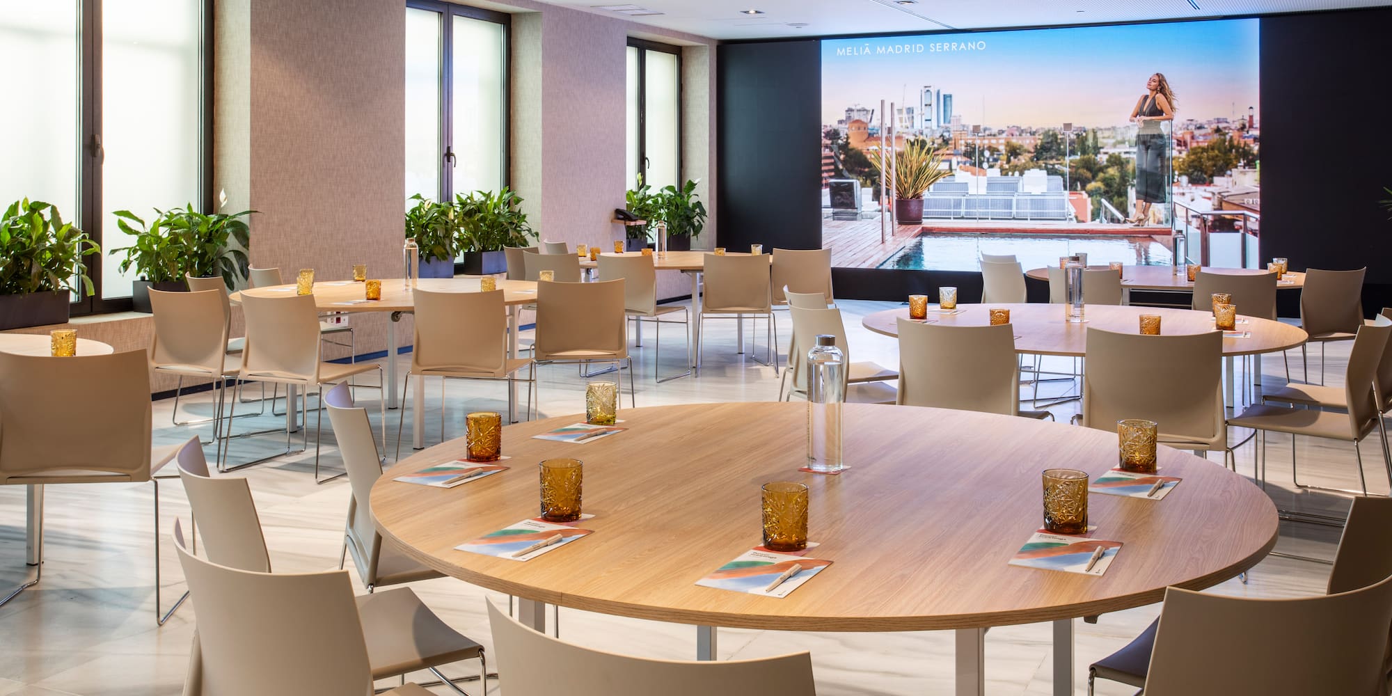 Melia Madrid Serrano meeting room with round tables and large screen.