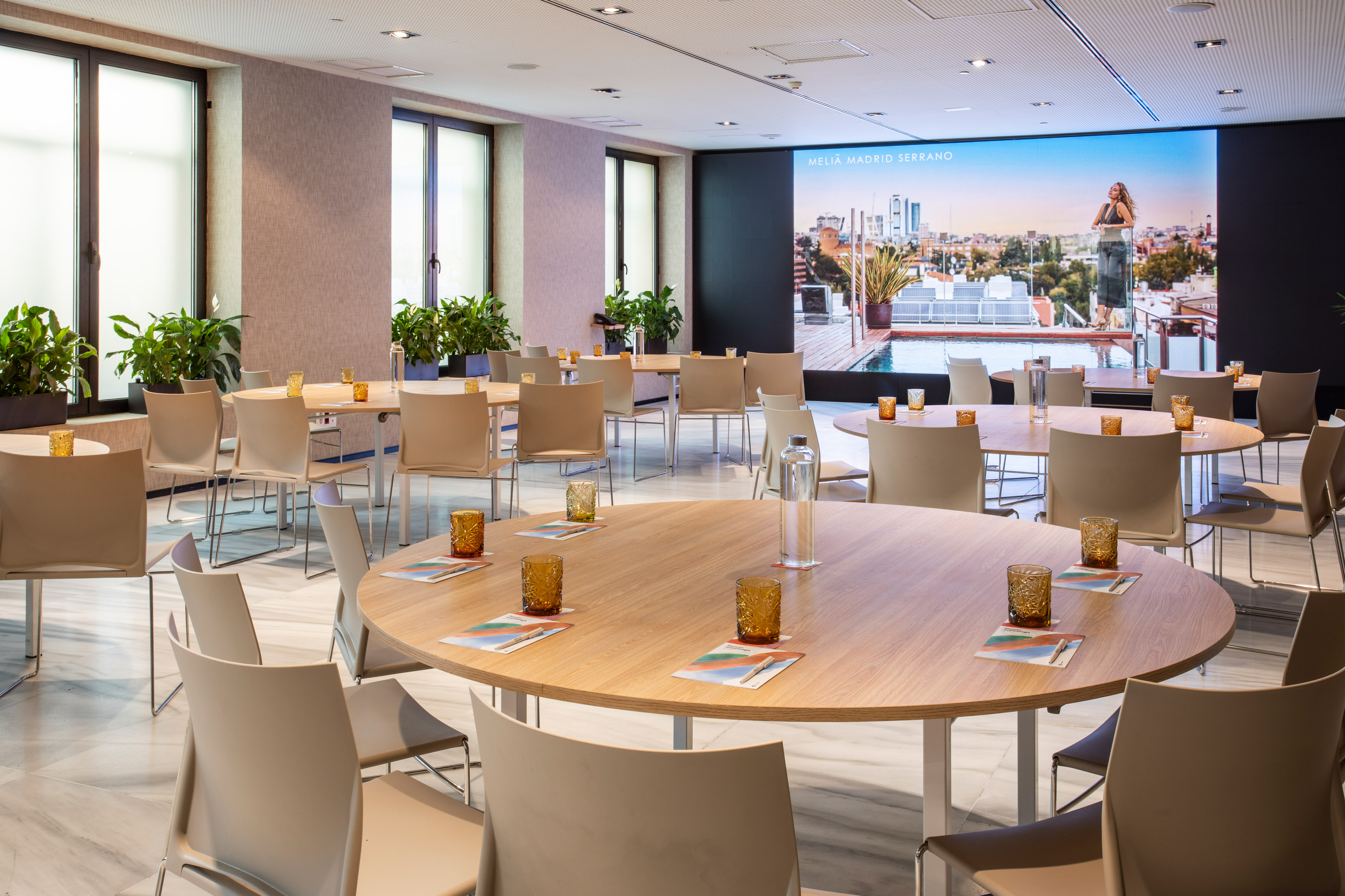 Melia Madrid Serrano meeting room with round tables and large screen.