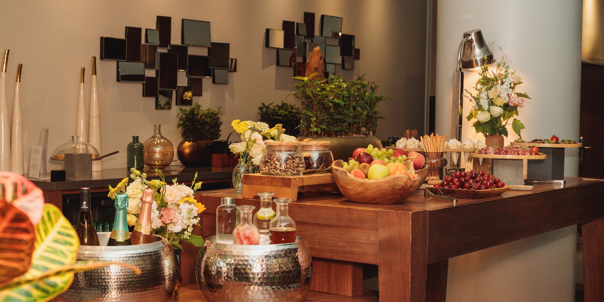 Stylish buffet table with fresh fruit, champagne, charcuterie, and modern decor.