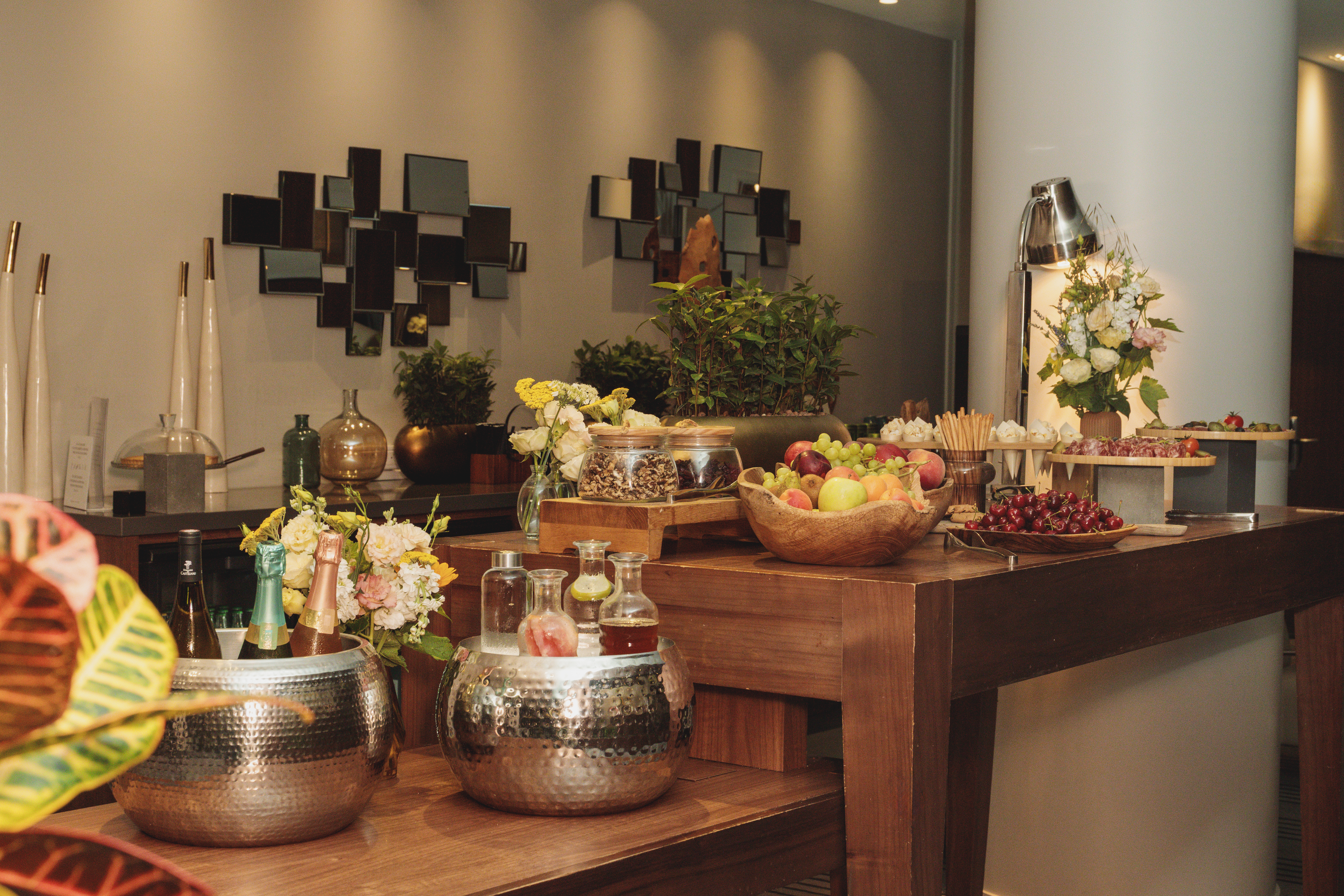 Stylish buffet table with fresh fruit, champagne, charcuterie, and modern decor.