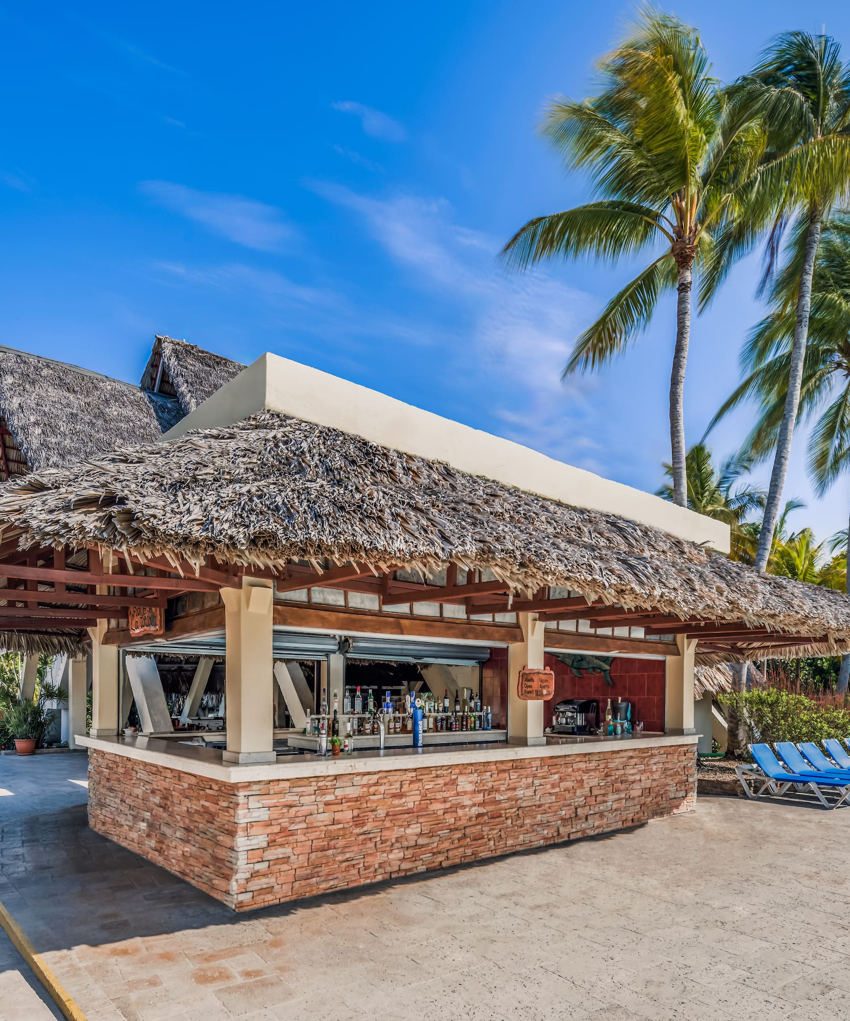 a bar with a thatched roof and lounge chairs