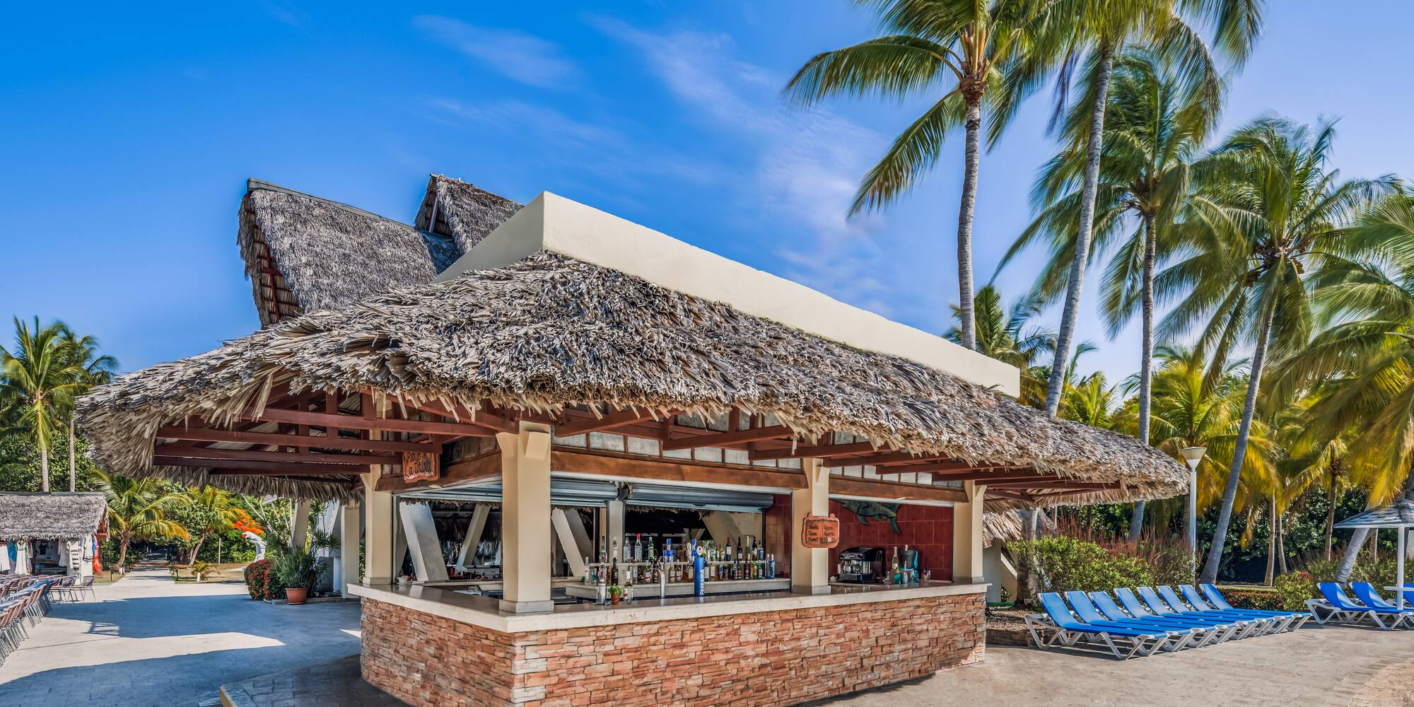 a bar with a thatched roof and lounge chairs