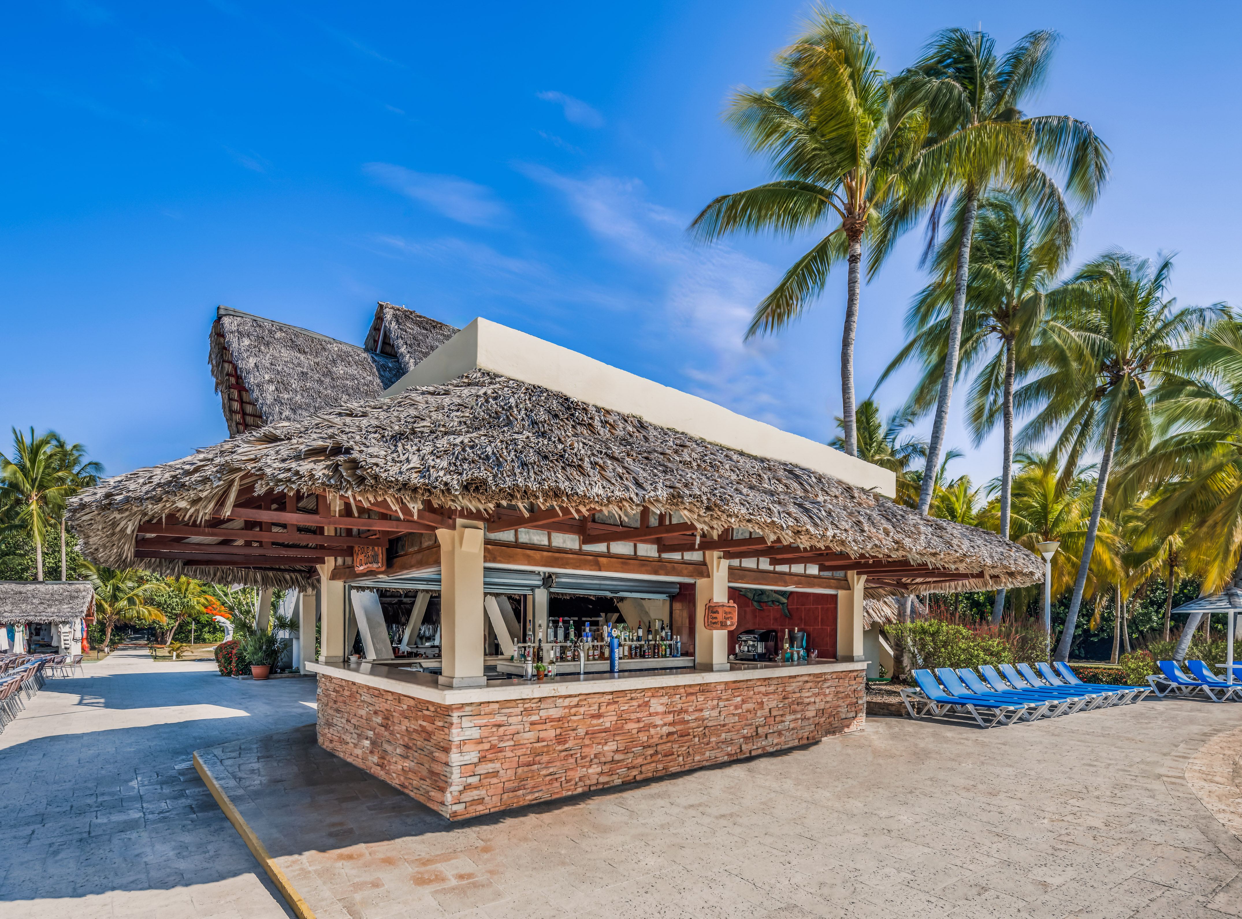 a bar with a thatched roof and lounge chairs