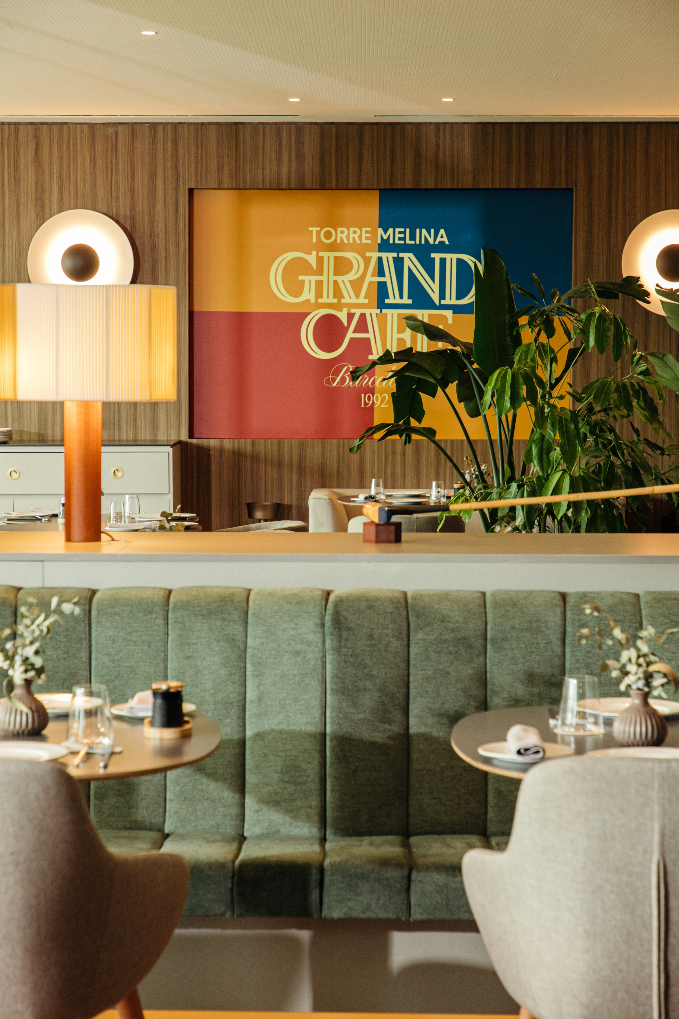 Modern cafe interior with green booth seating, Grand Cafe sign, and elegant tables.