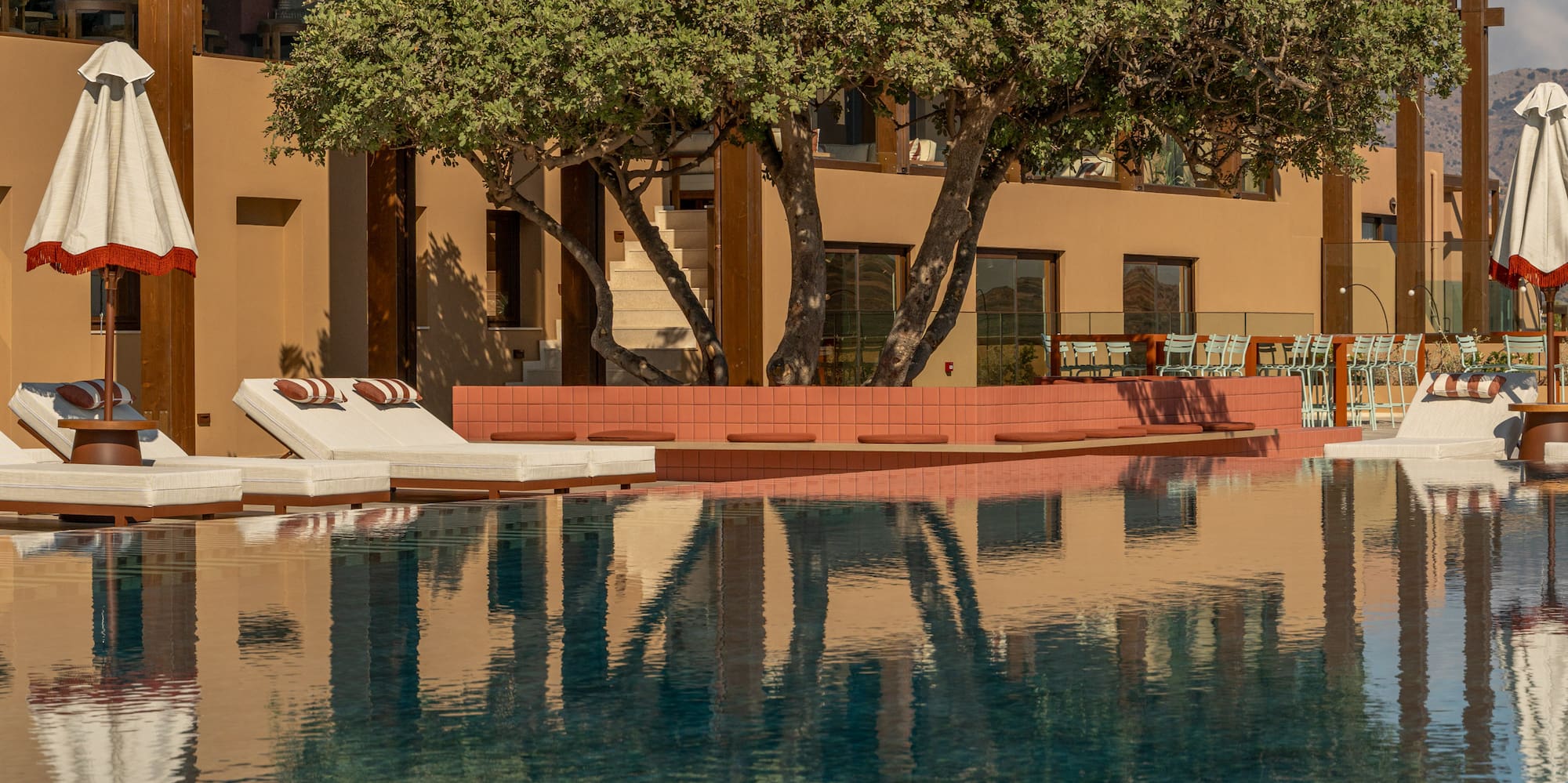 a pool with umbrellas and chairs in front of a building