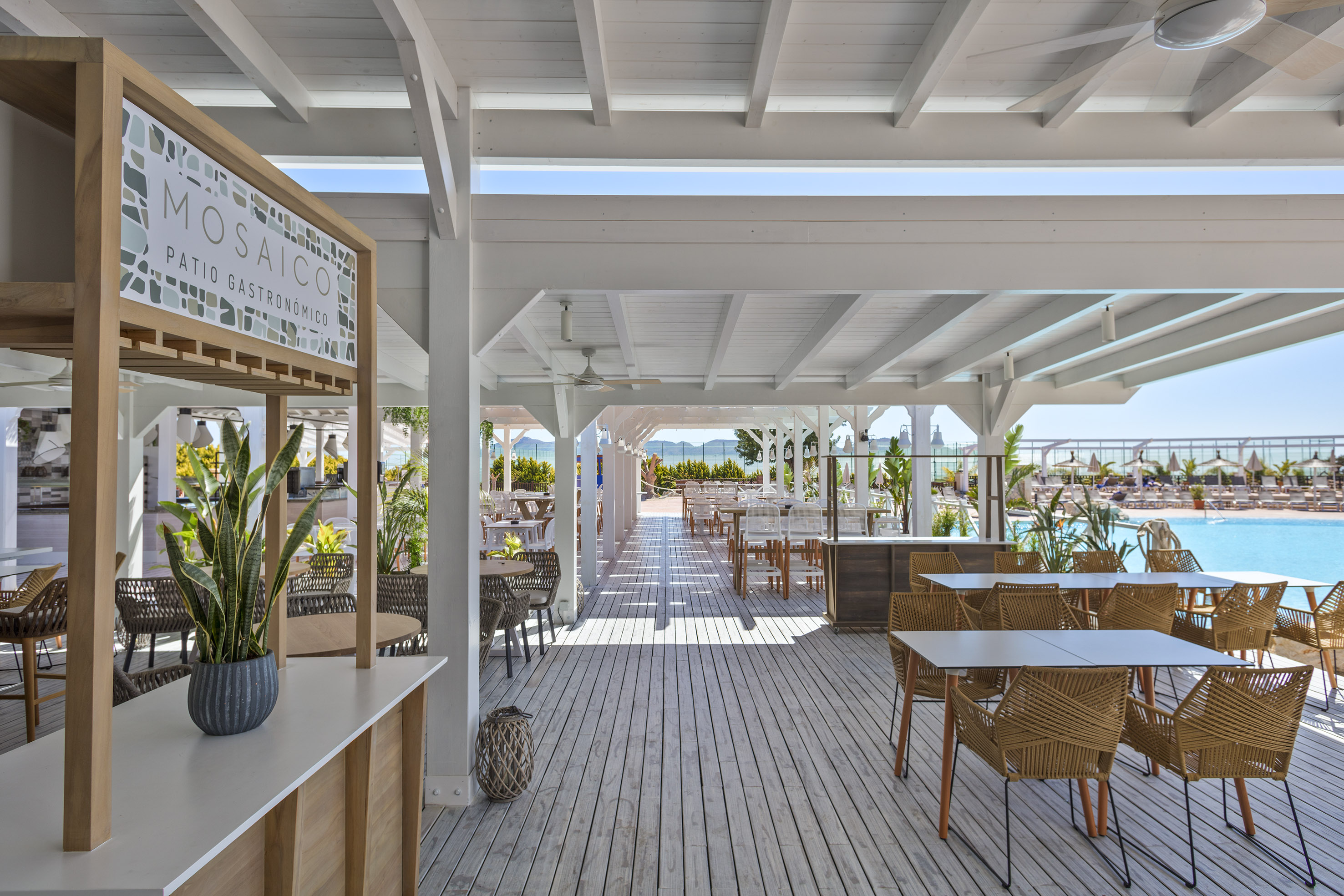Mosaico outdoor patio restaurant with wooden deck, pool, and ocean views.