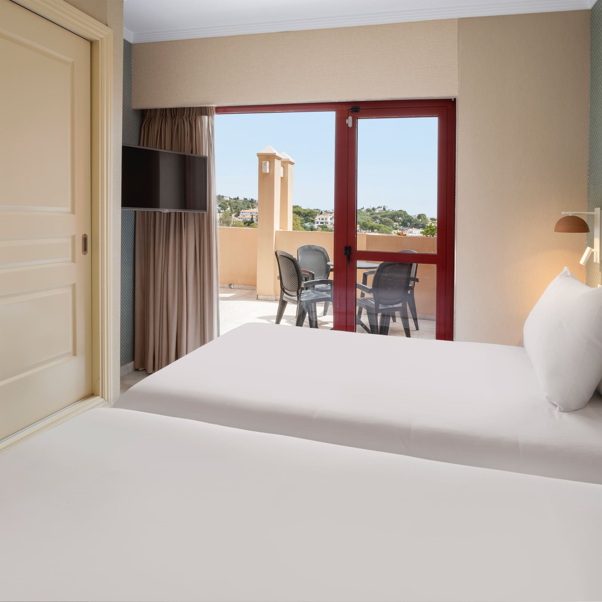 Resort twin bedroom with balcony, outdoor chairs, and woven headboard.