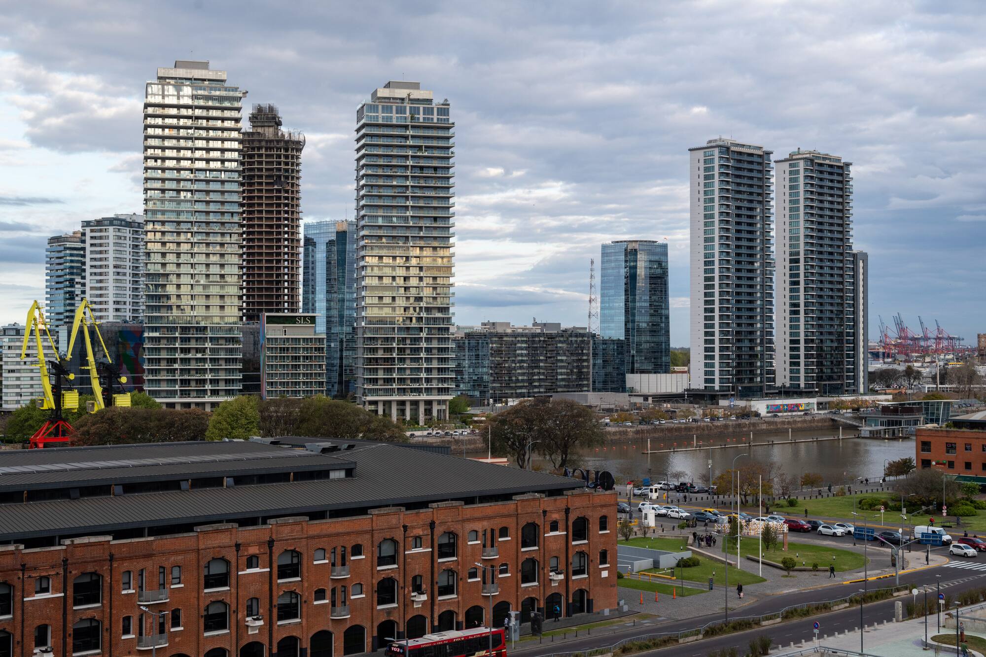 Modern skyscrapers and historic brick building along a city waterfront.