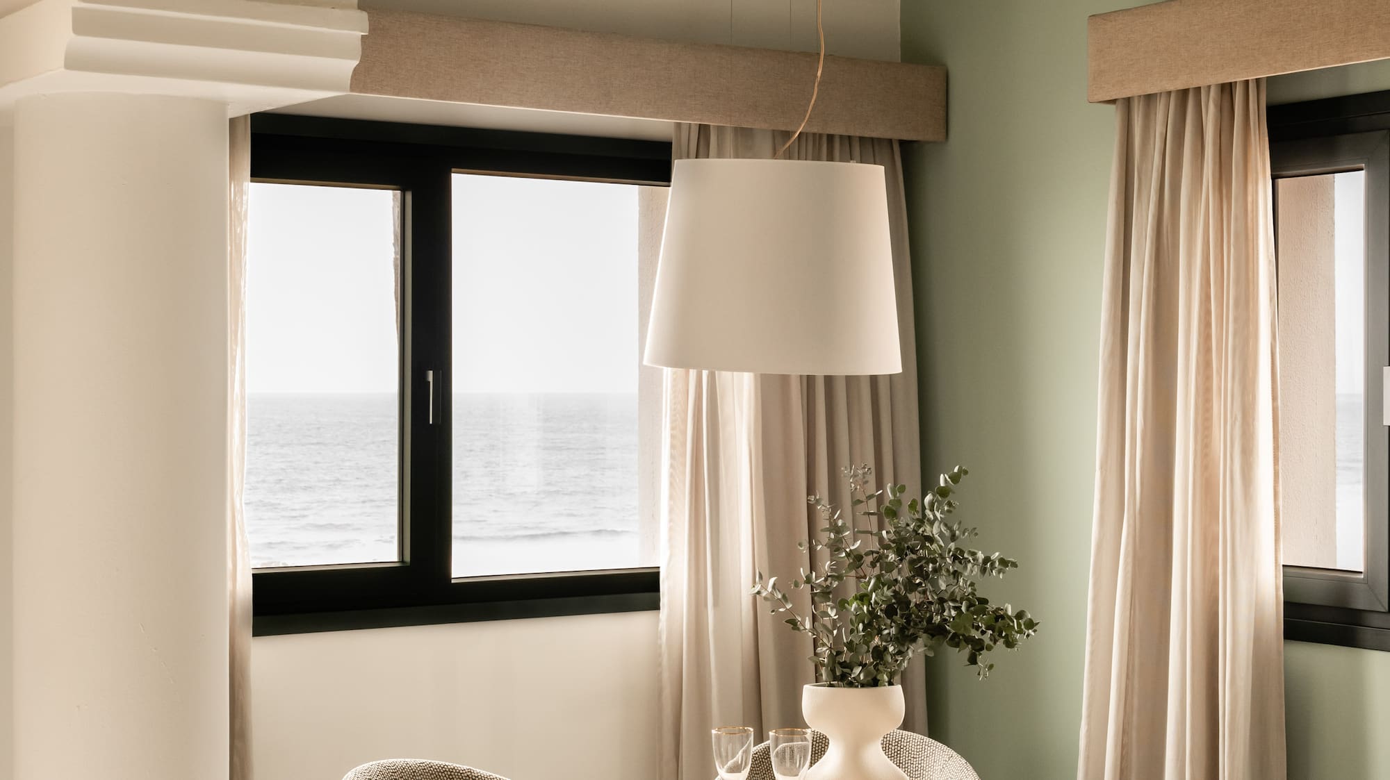 a dining table with chairs in a room with a window and ocean view