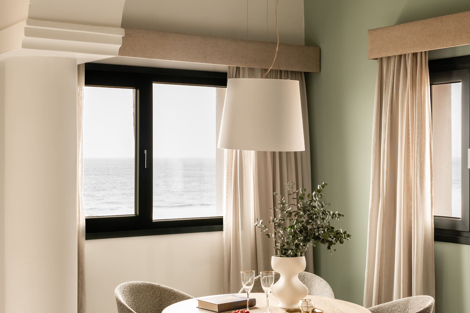 a dining table with chairs in a room with a window and ocean view