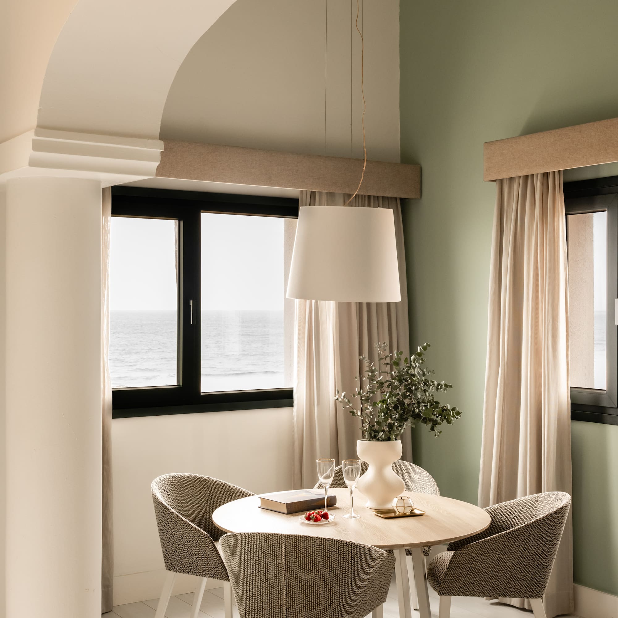 a dining table with chairs in a room with a window and ocean view