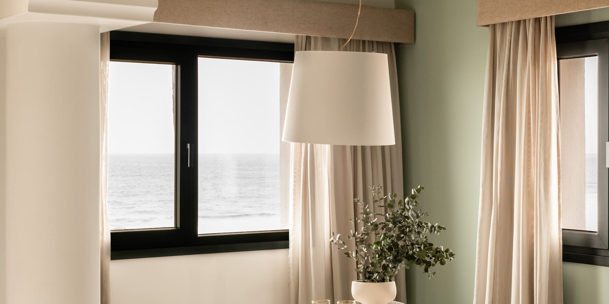 a dining table with chairs in a room with a window and ocean view