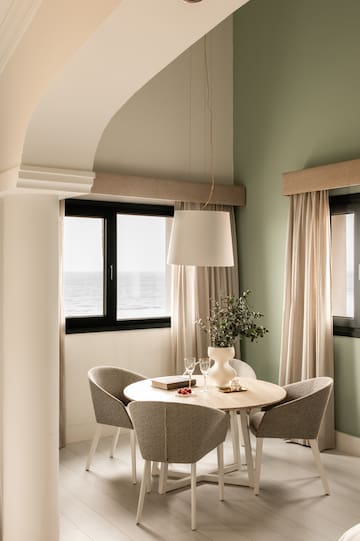 a dining table with chairs in a room with a window and ocean view
