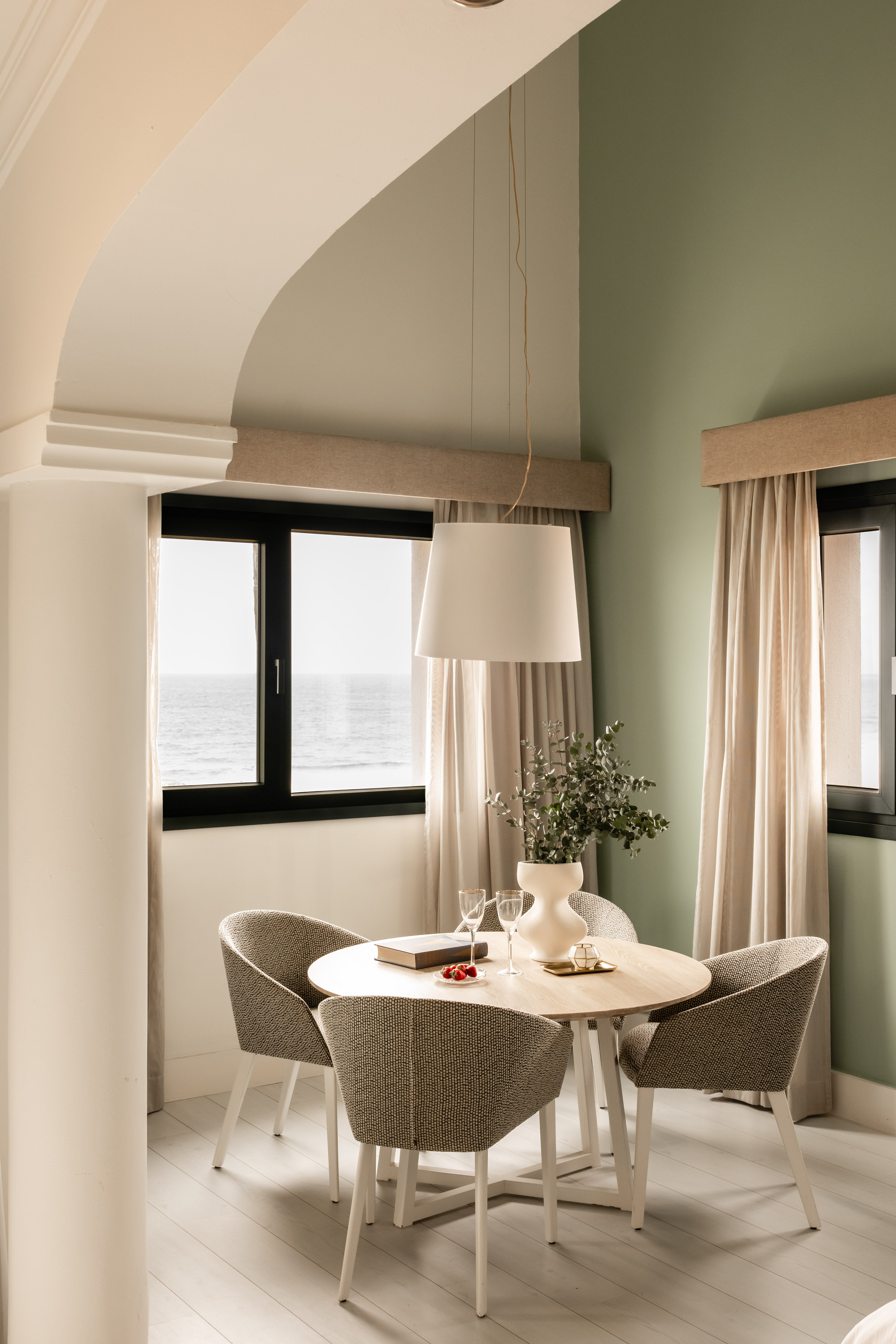 a dining table with chairs in a room with a window and ocean view