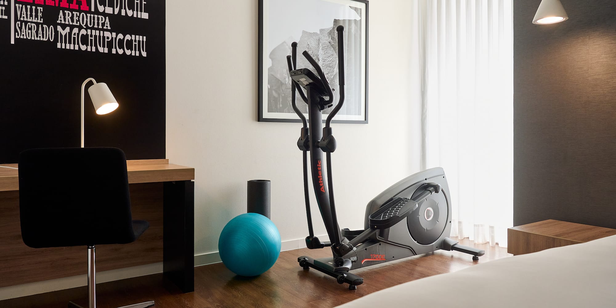a room with exercise equipment and a bed and a lamp