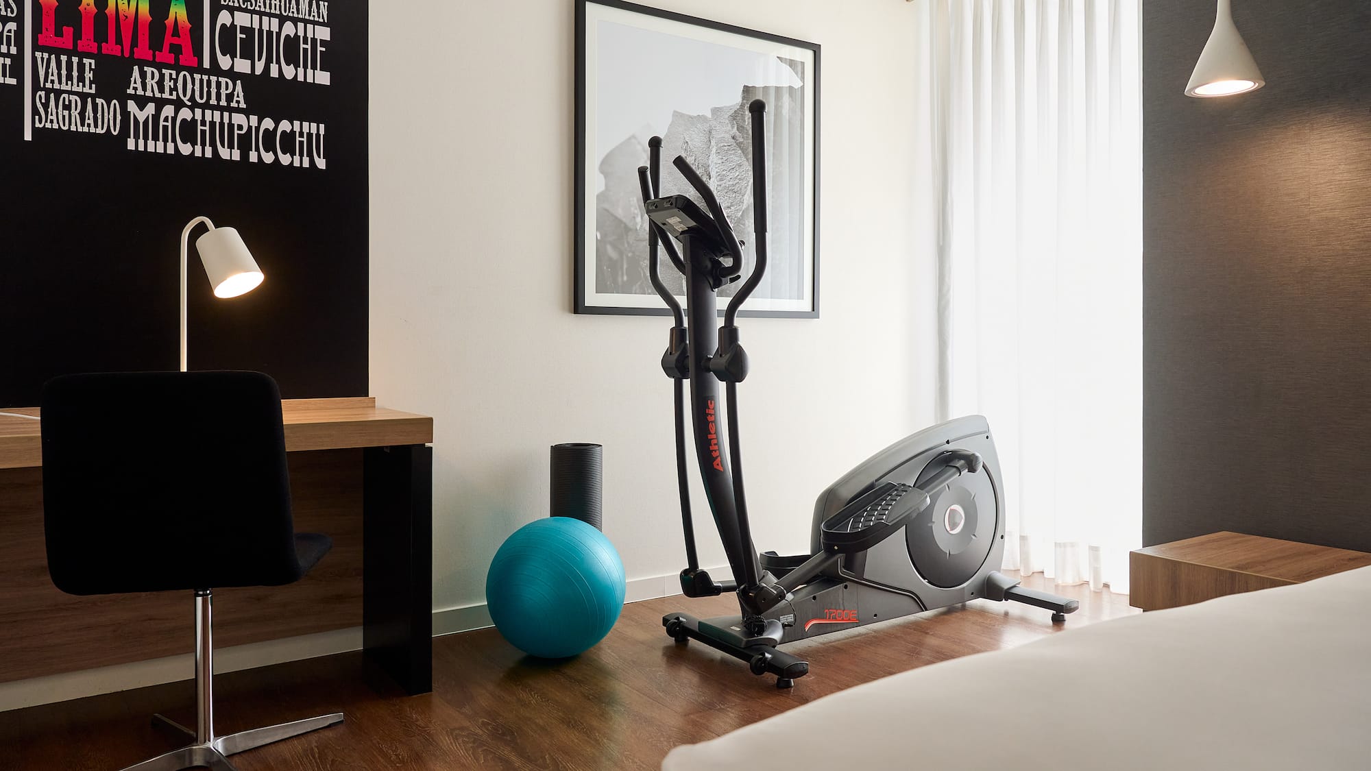 a room with exercise equipment and a bed and a lamp