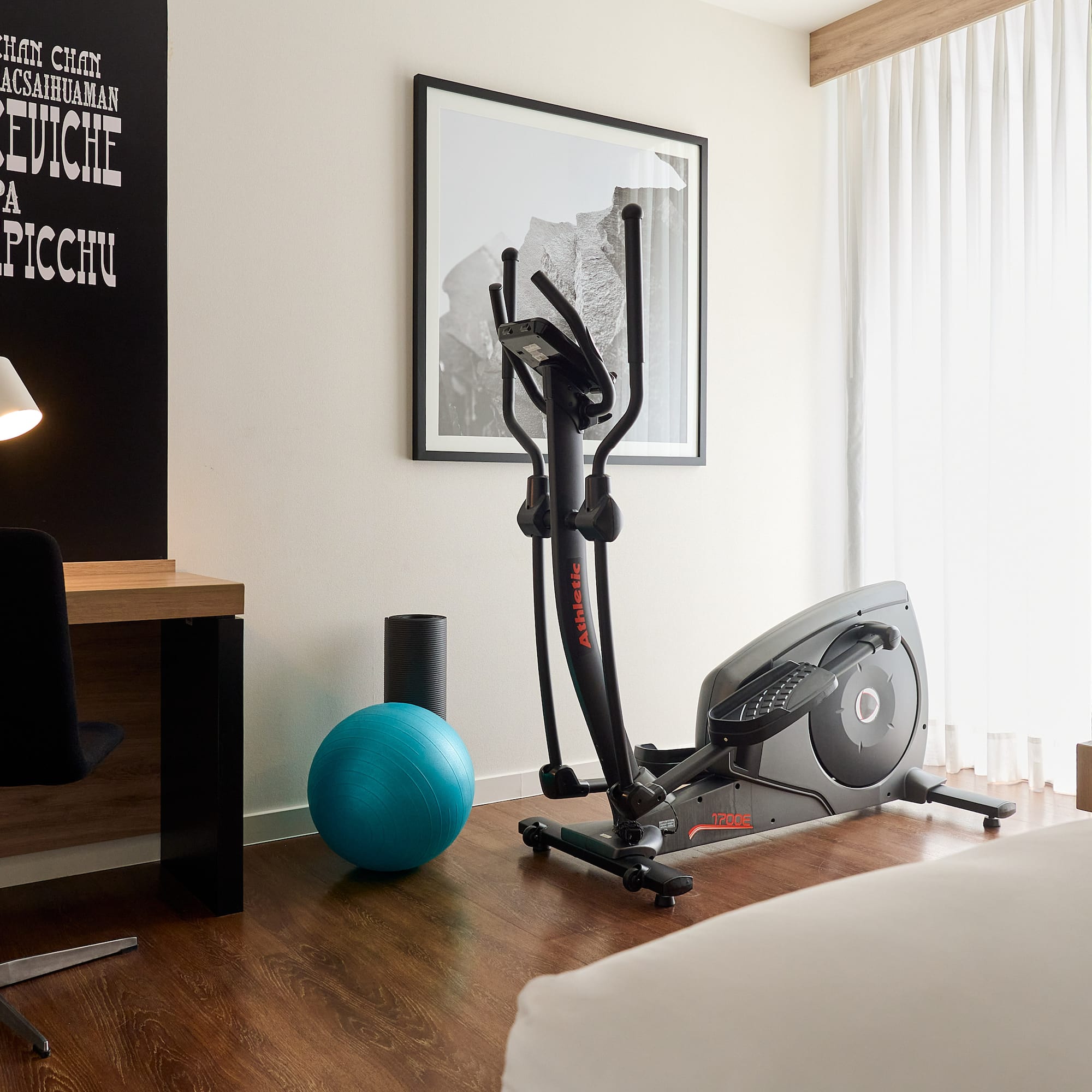 a room with exercise equipment and a bed and a lamp