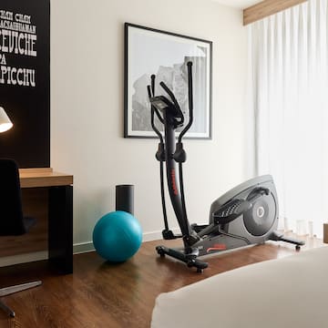 a room with exercise equipment and a bed and a lamp