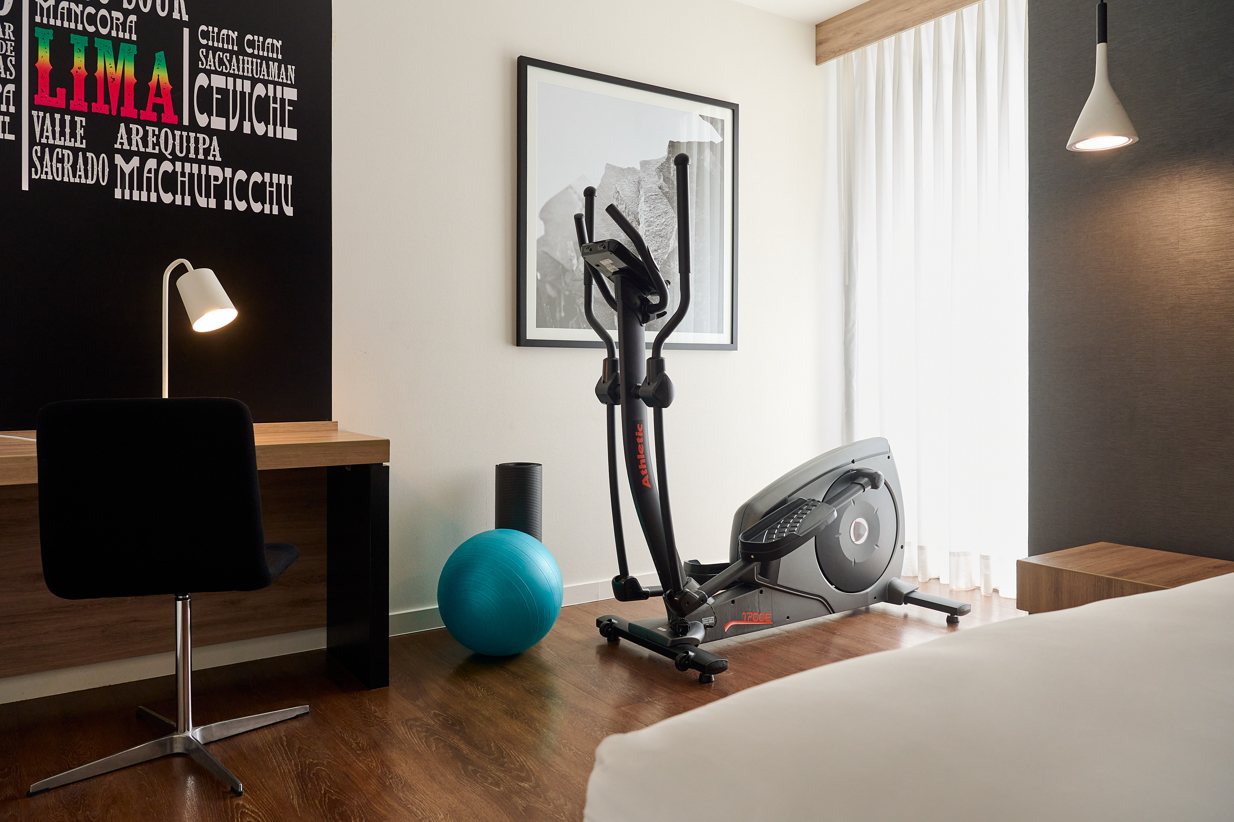 a room with exercise equipment and a bed and a lamp