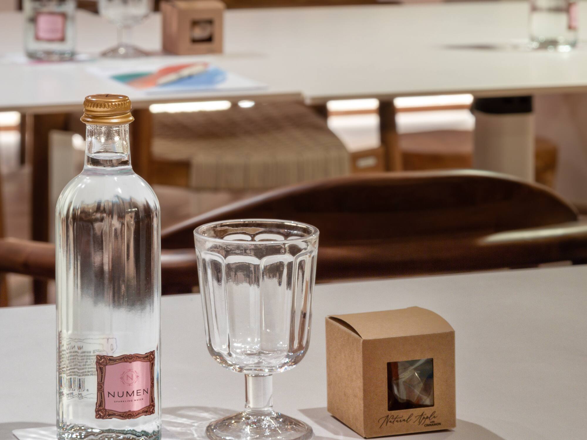 Configuración de mesa para reunión: agua Numen, vaso, snack y folleto Meliá.