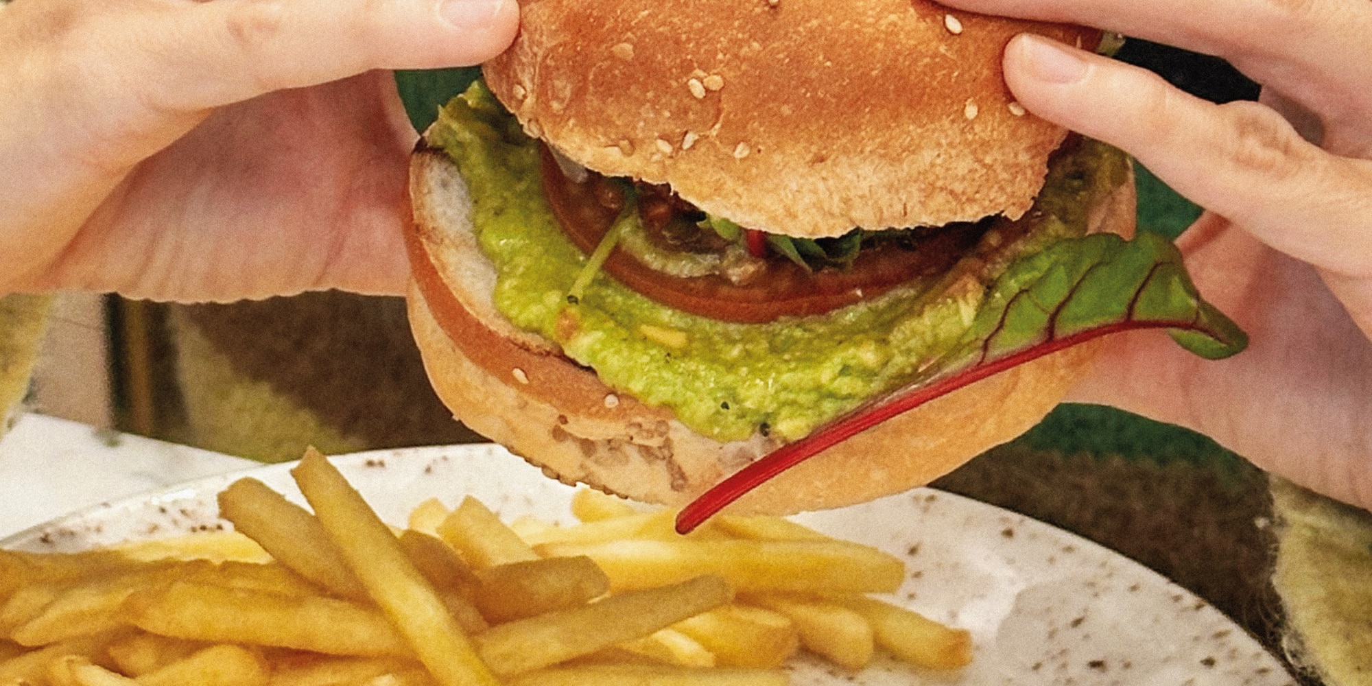 a person holding a burger and fries