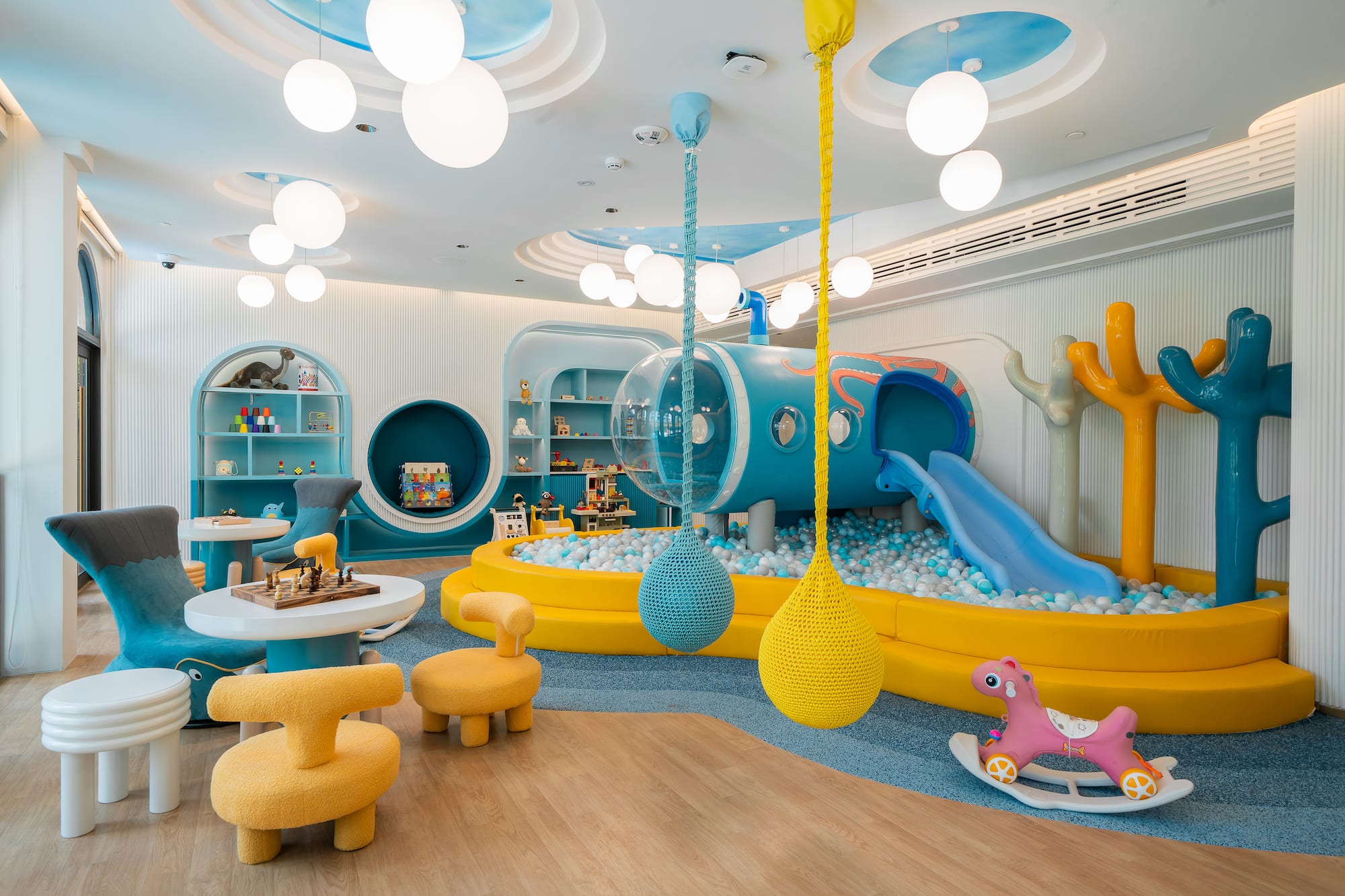 Vibrant indoor children's play area with ball pit, slide, and activity stations.