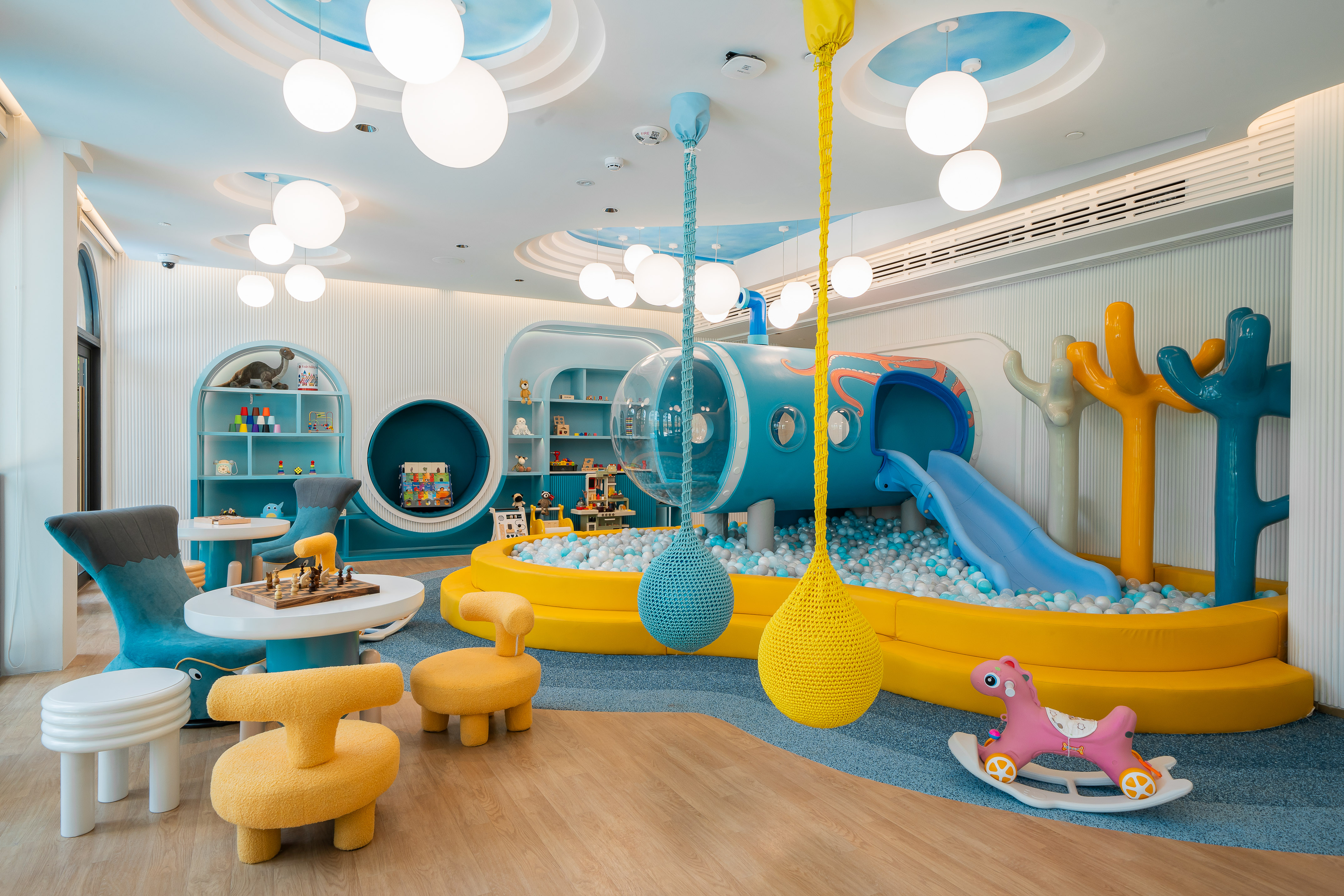 Vibrant indoor children's play area with ball pit, slide, and activity stations.