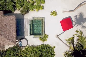 a pool and a red umbrella on a beach