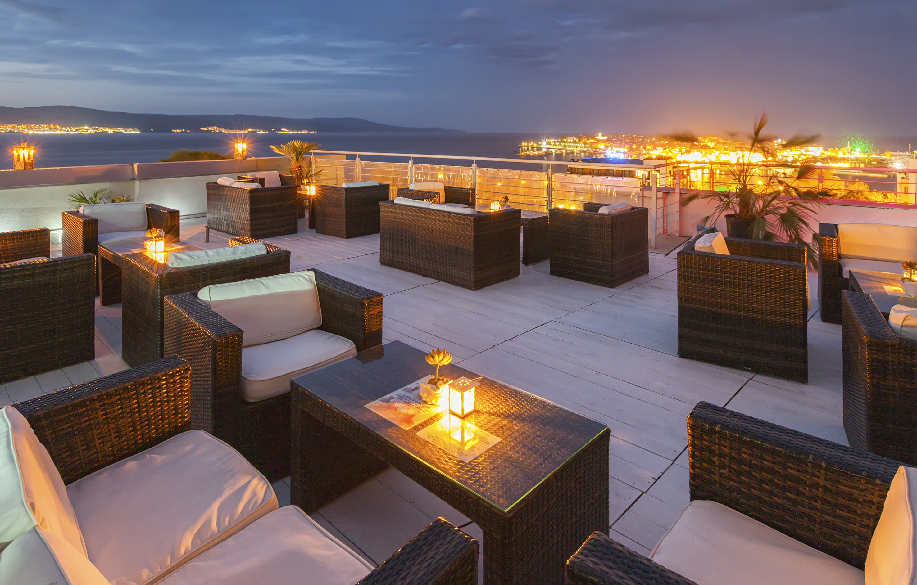a patio with chairs and tables and lights on the deck