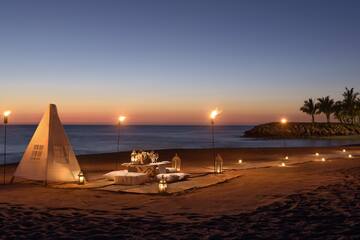 a tent and table set up on a beach with lit candles