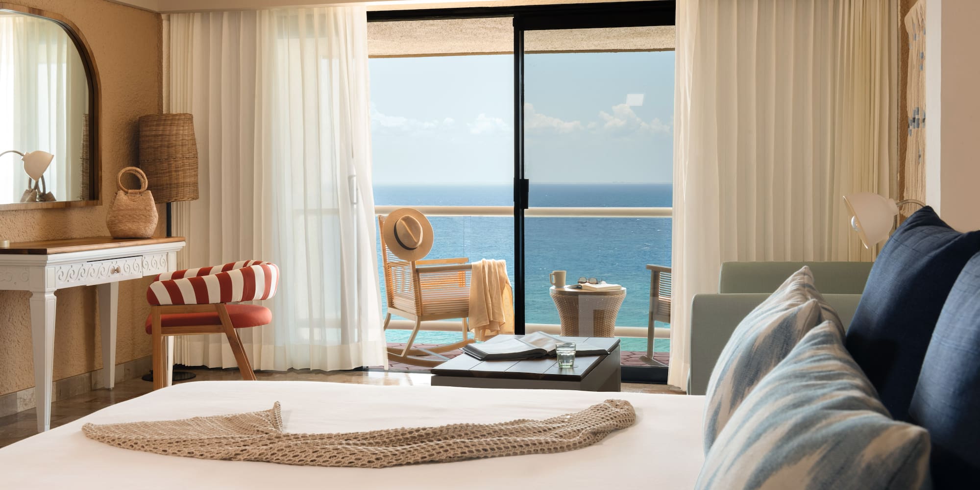 Hotel room with ocean view balcony, bed, and stylish coastal decor.