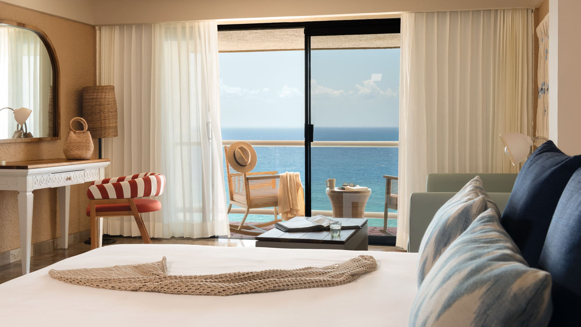 Hotel room with ocean view balcony, bed, and stylish coastal decor.