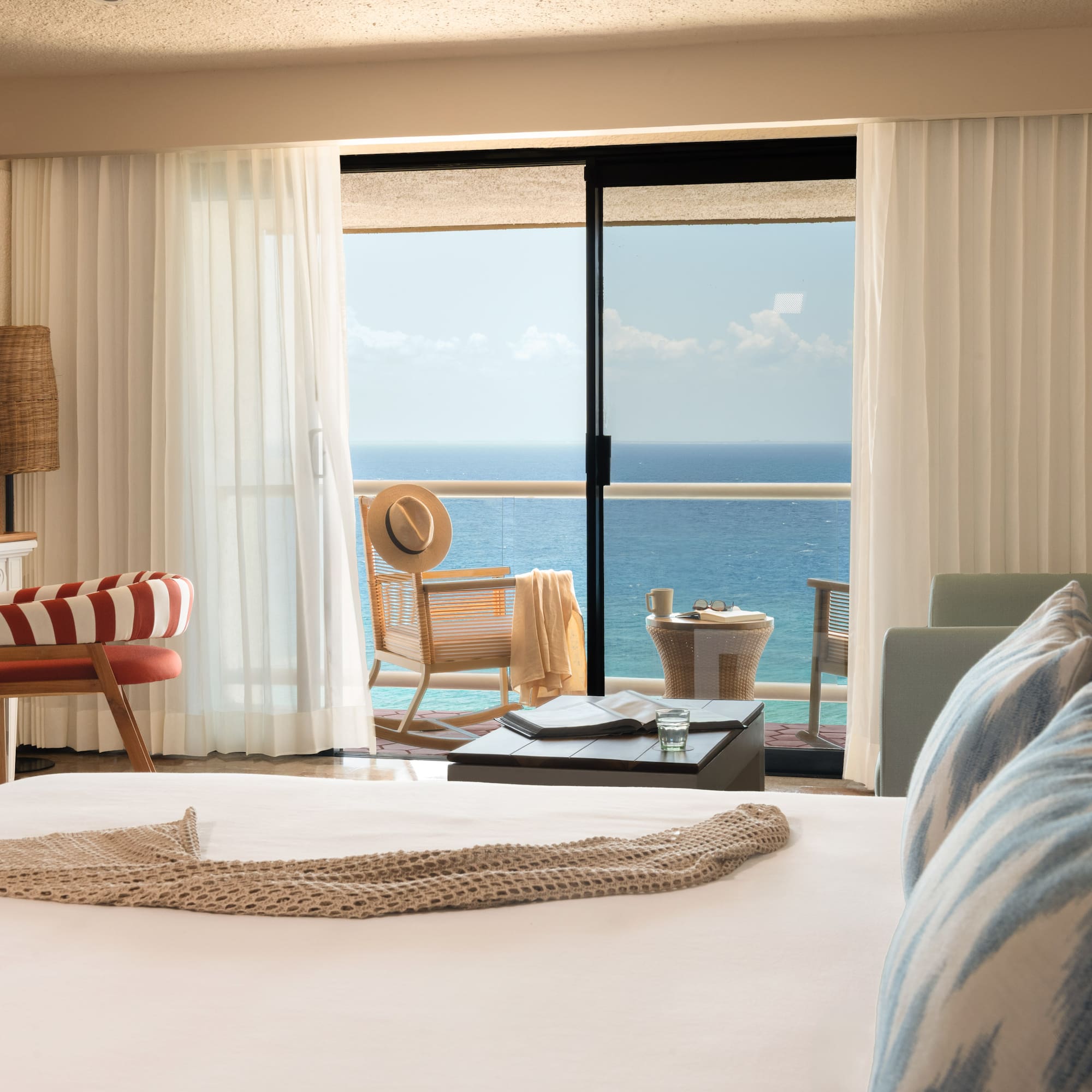 Hotel room with ocean view balcony, bed, and stylish coastal decor.