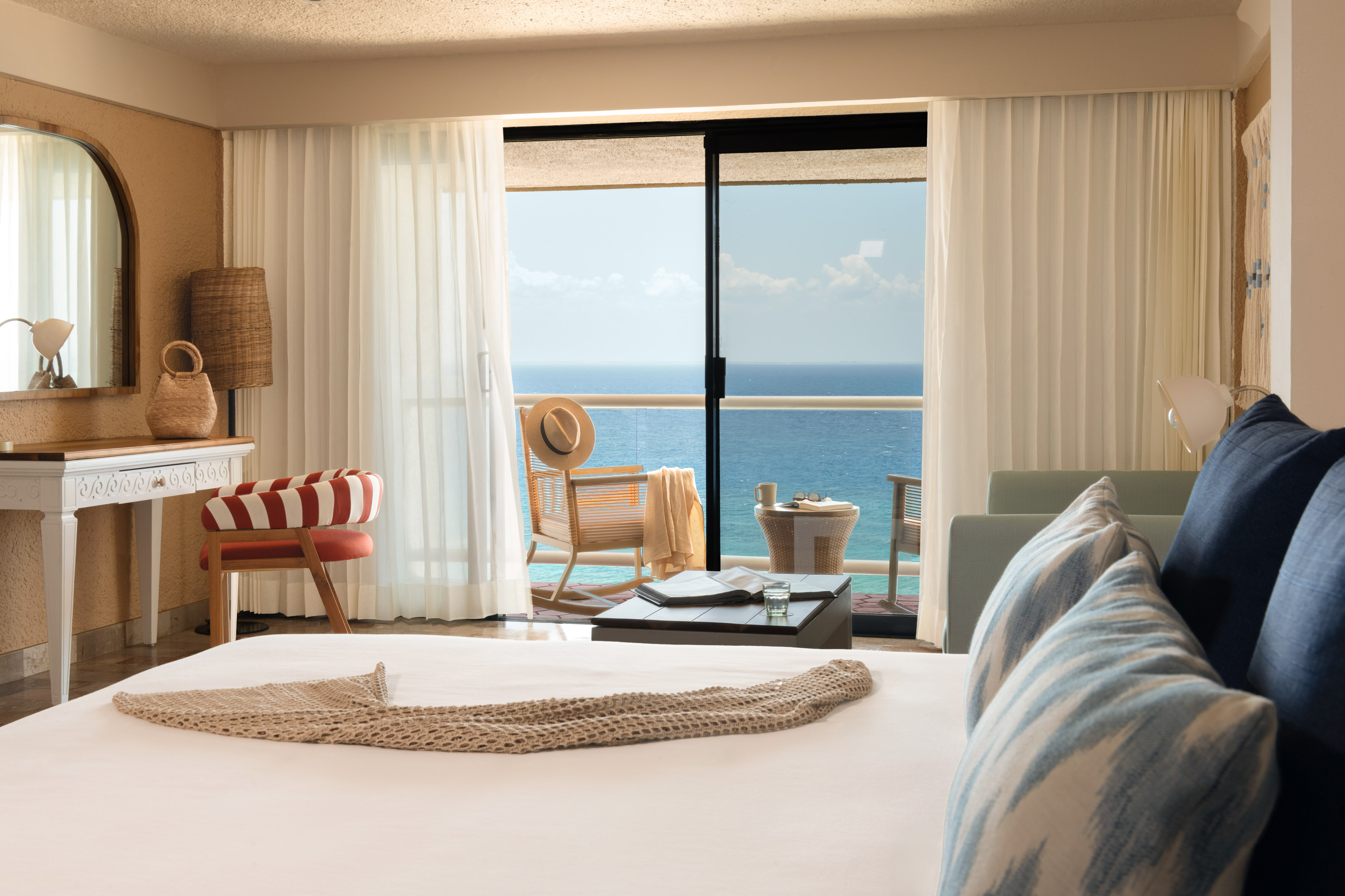 Hotel room with ocean view balcony, bed, and stylish coastal decor.