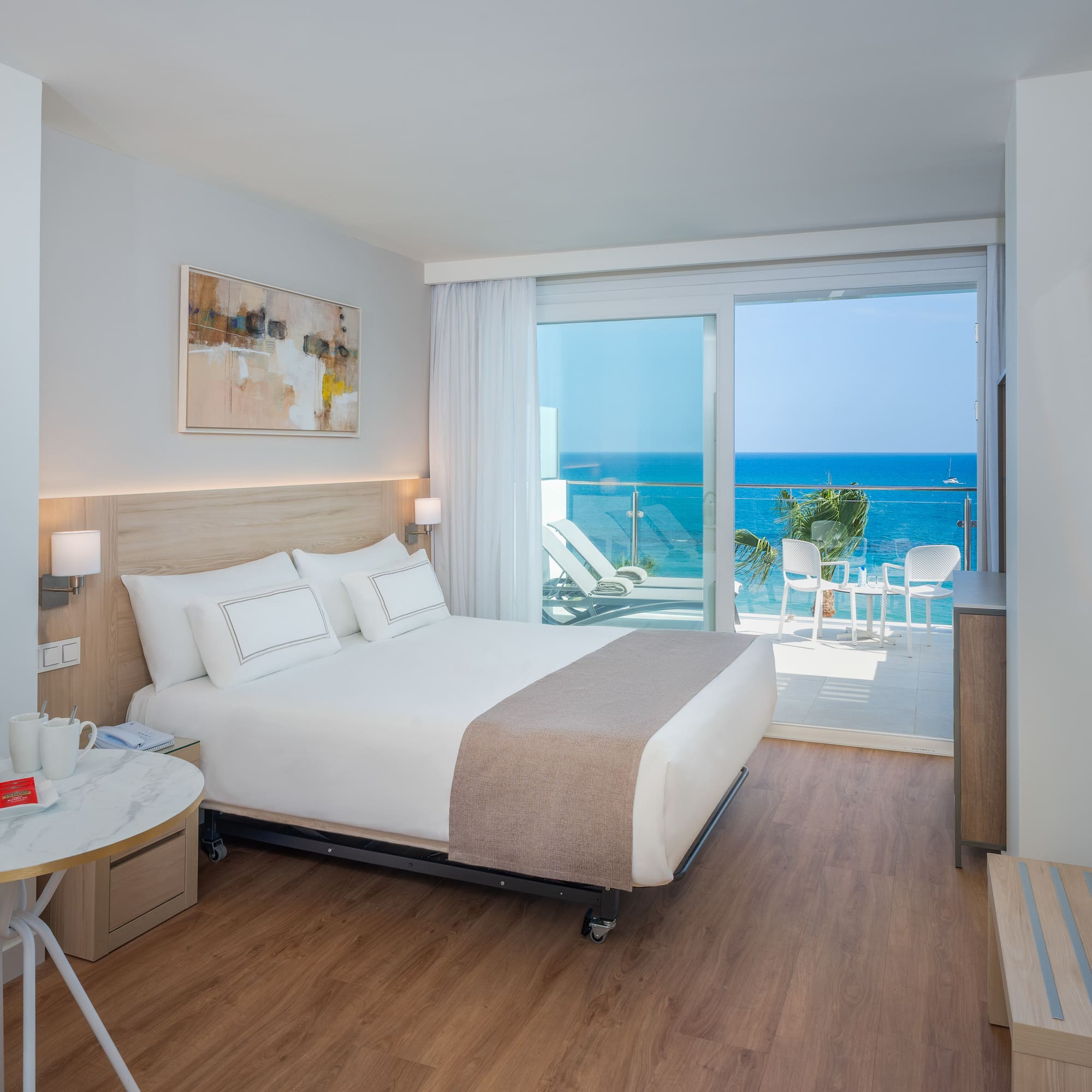 Modern hotel room with ocean view balcony, large bed, and stylish decor.