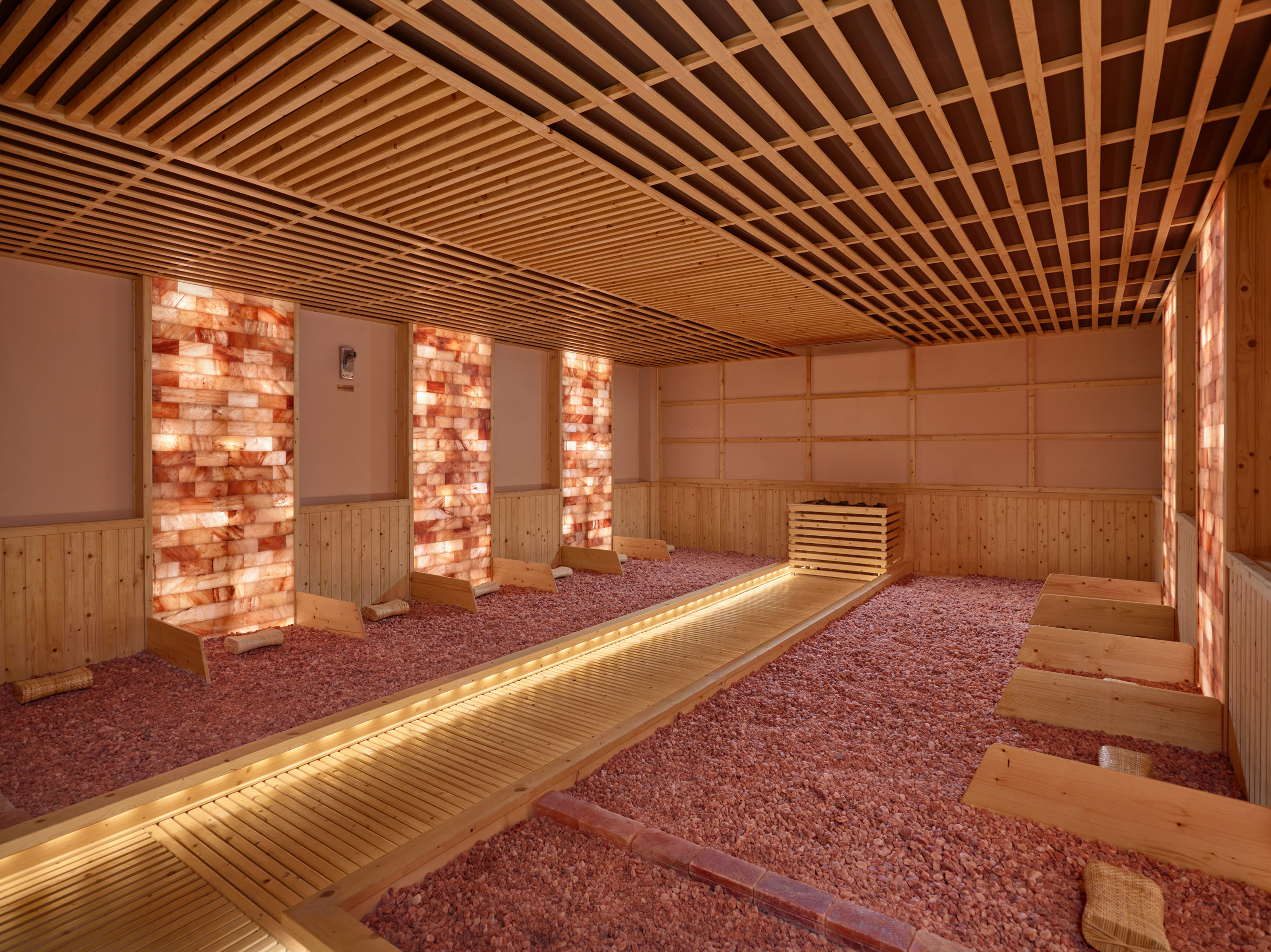 Himalayan salt room with glowing salt walls, salt pebble floor, and wooden ceiling.