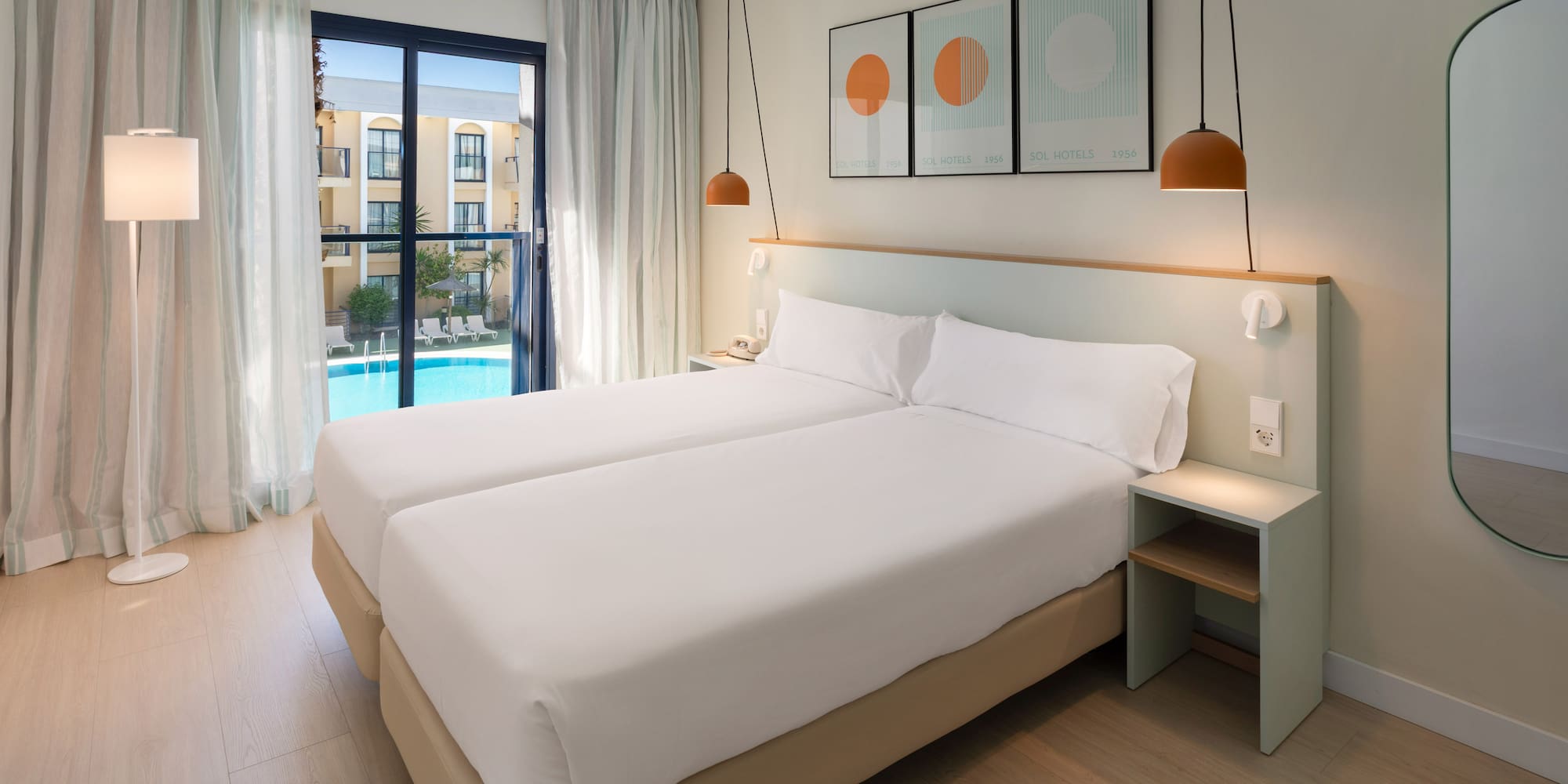 a room with two beds and a pool in the background