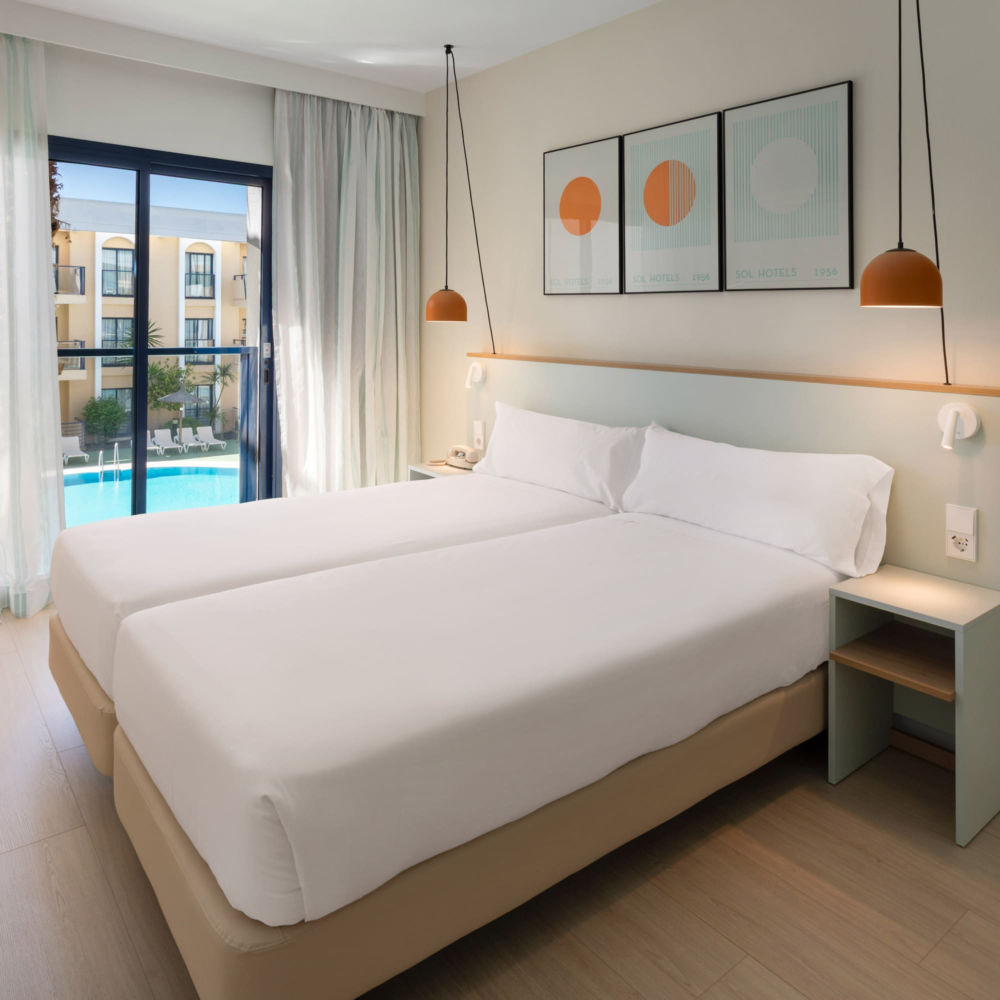 a room with two beds and a pool in the background