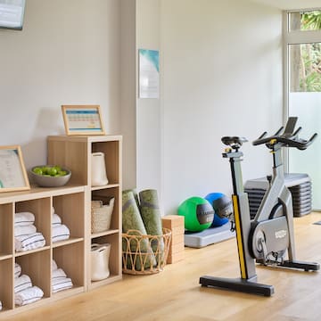a room with exercise bikes and shelves with towels