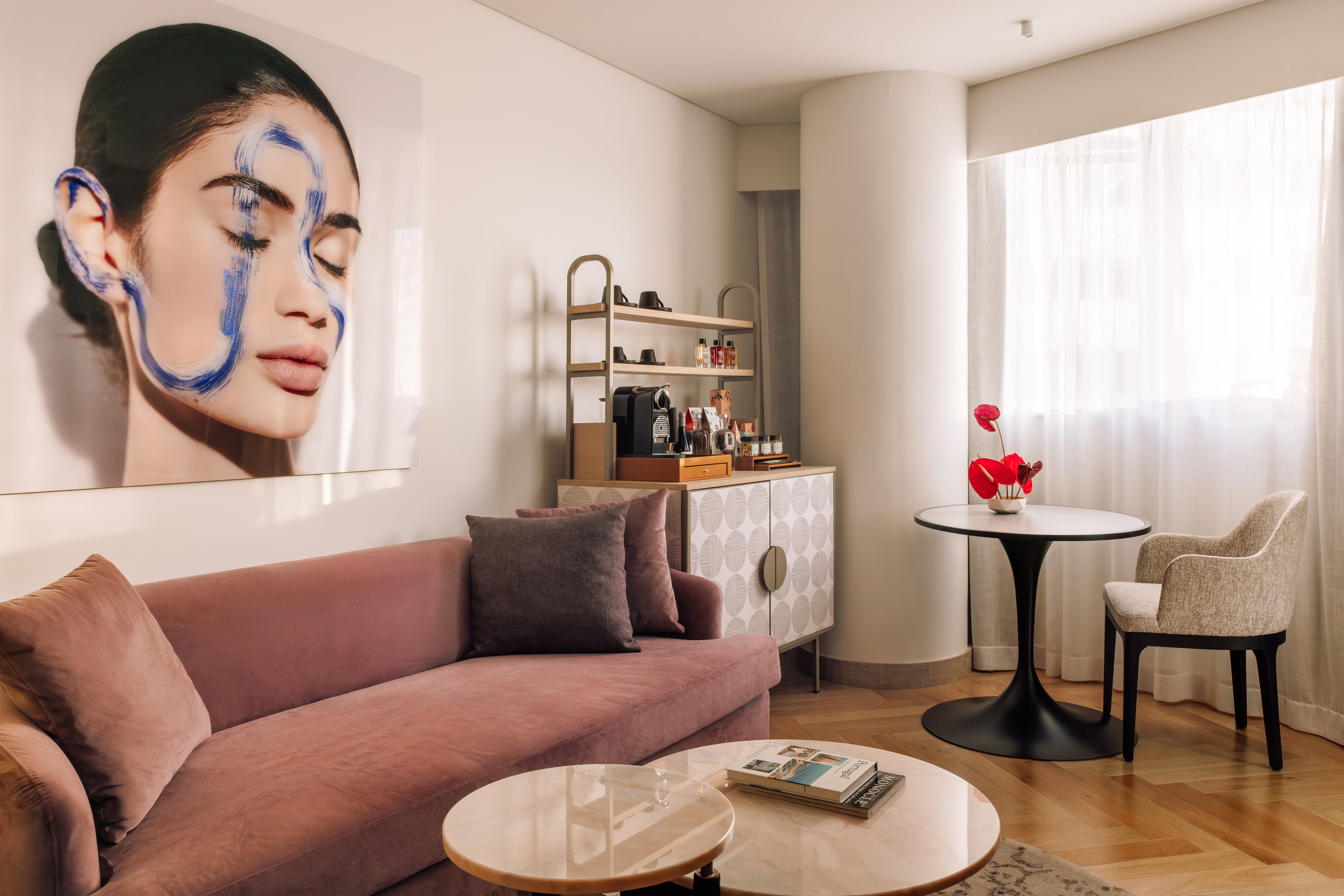 Luxury hotel suite interior with pink velvet sofa, modern art, coffee bar.