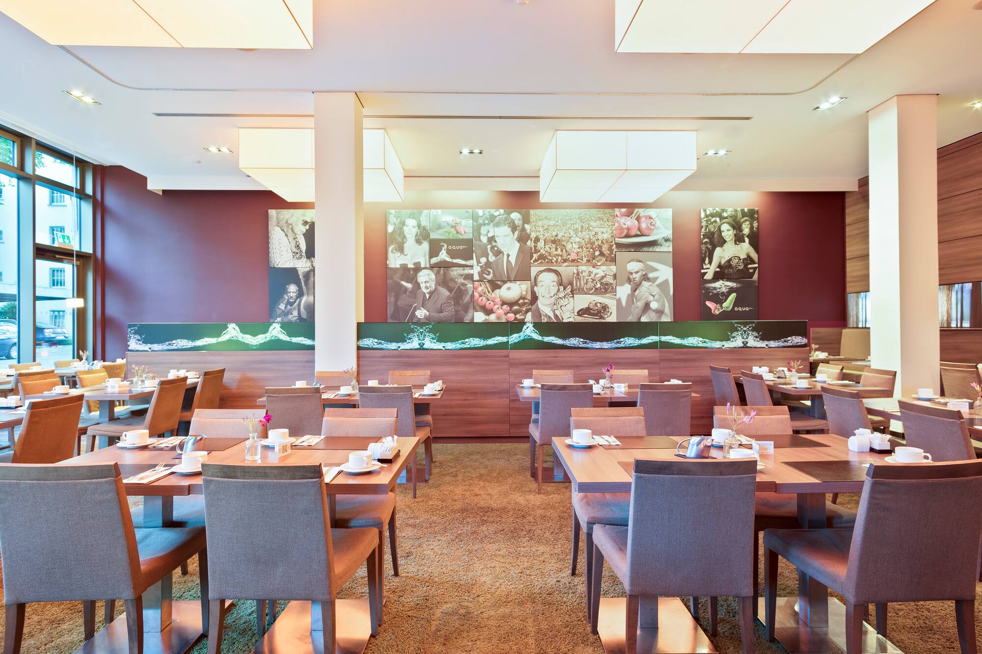 Modern hotel restaurant with set tables, maroon walls, and artistic murals.