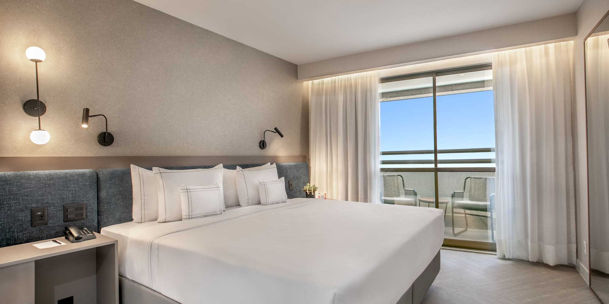 a bed with white sheets and pillows in a hotel room