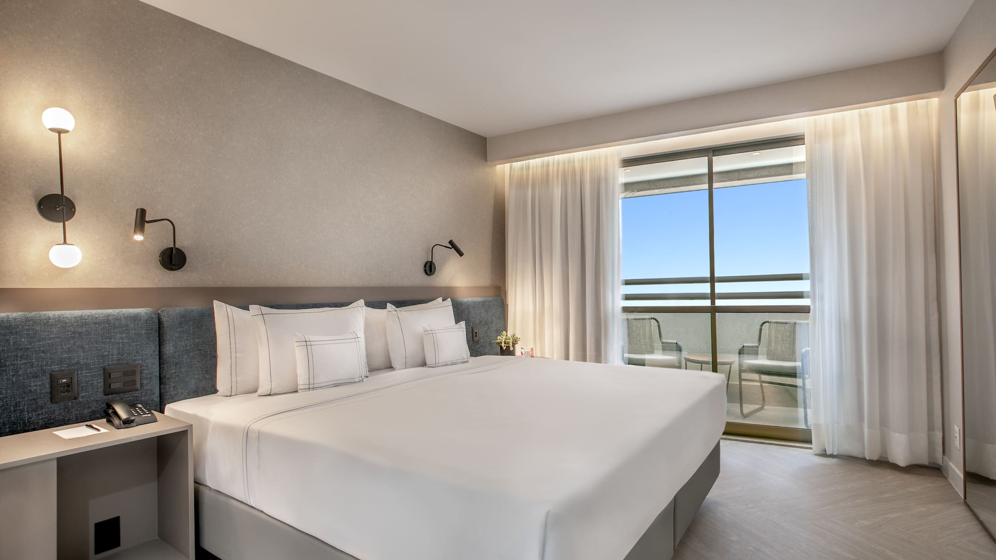 a bed with white sheets and pillows in a hotel room