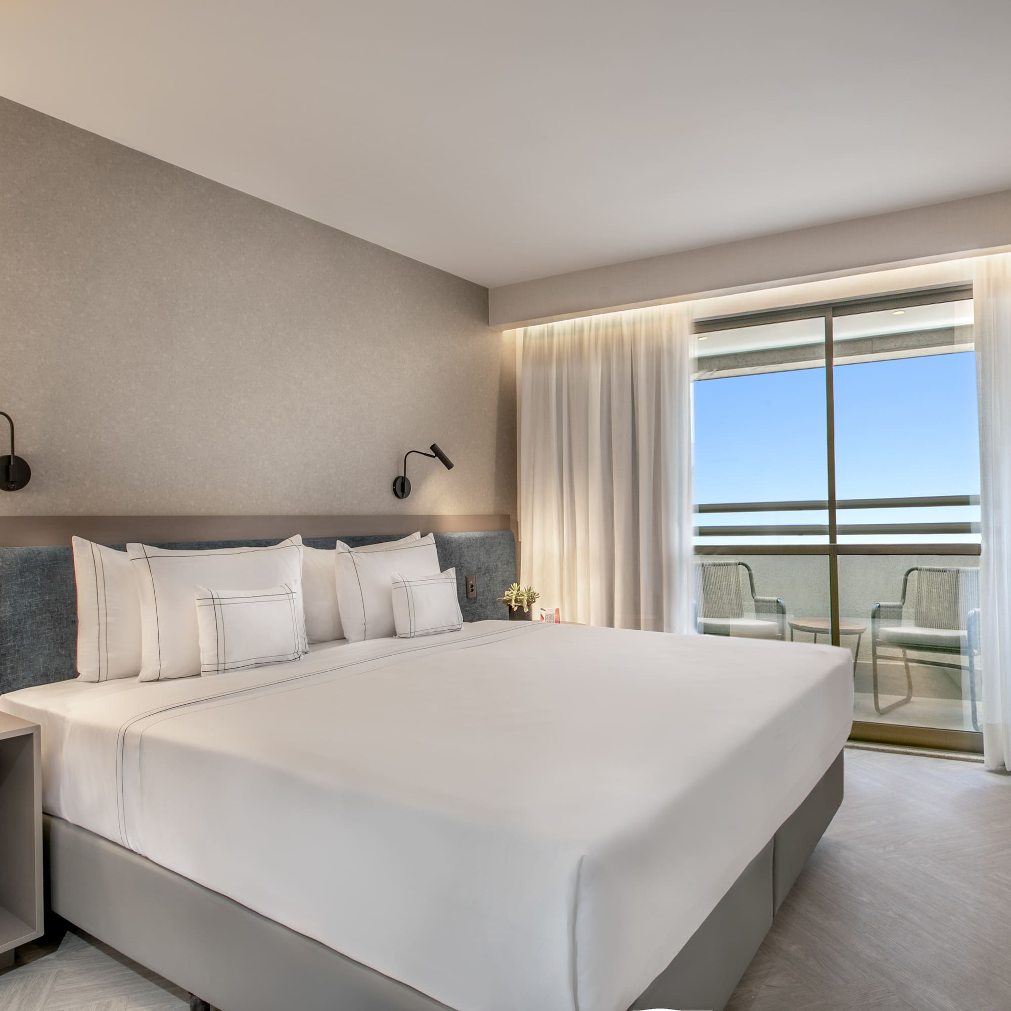 a bed with white sheets and pillows in a hotel room