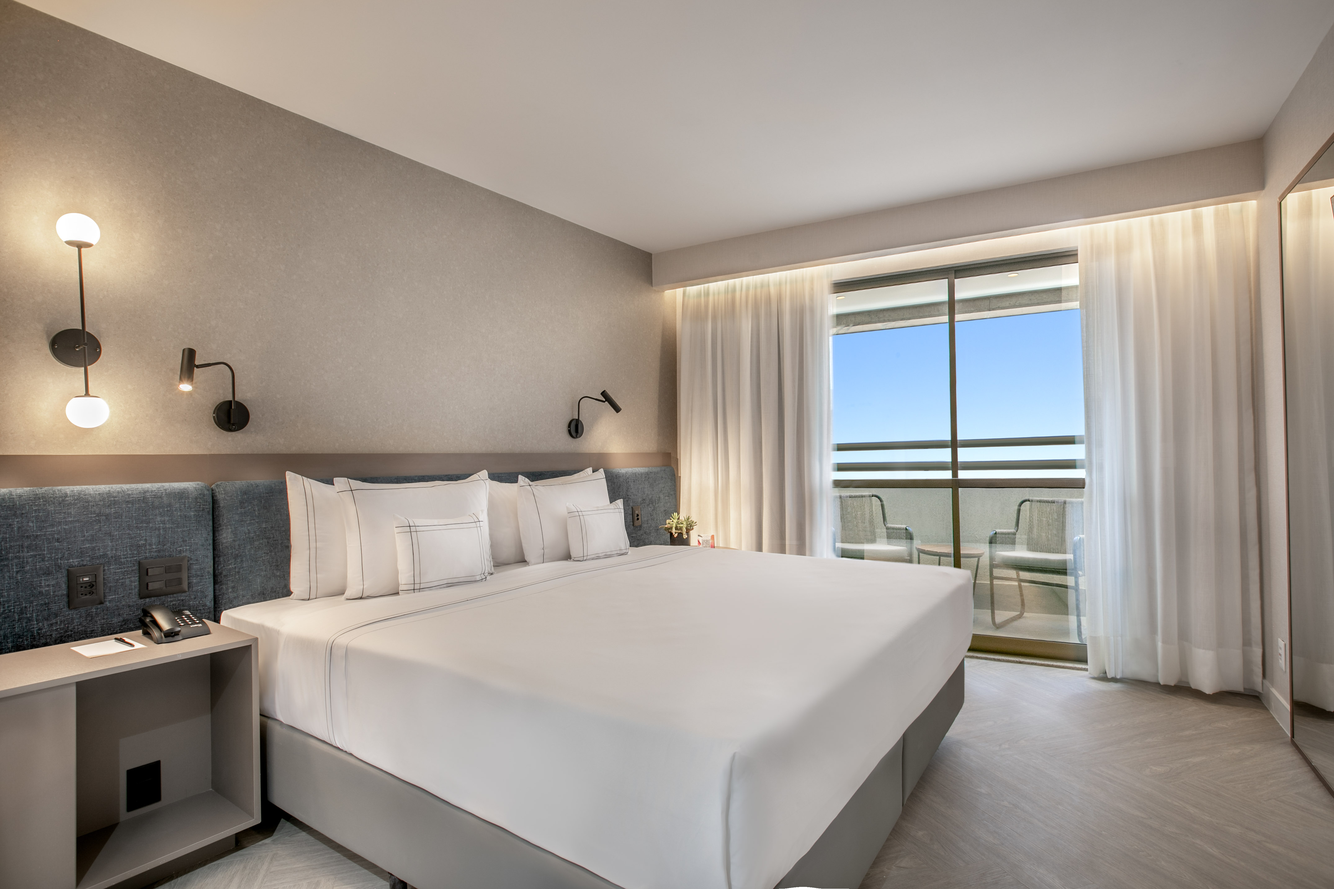 Modern hotel bedroom with king bed, contemporary decor, and balcony access.