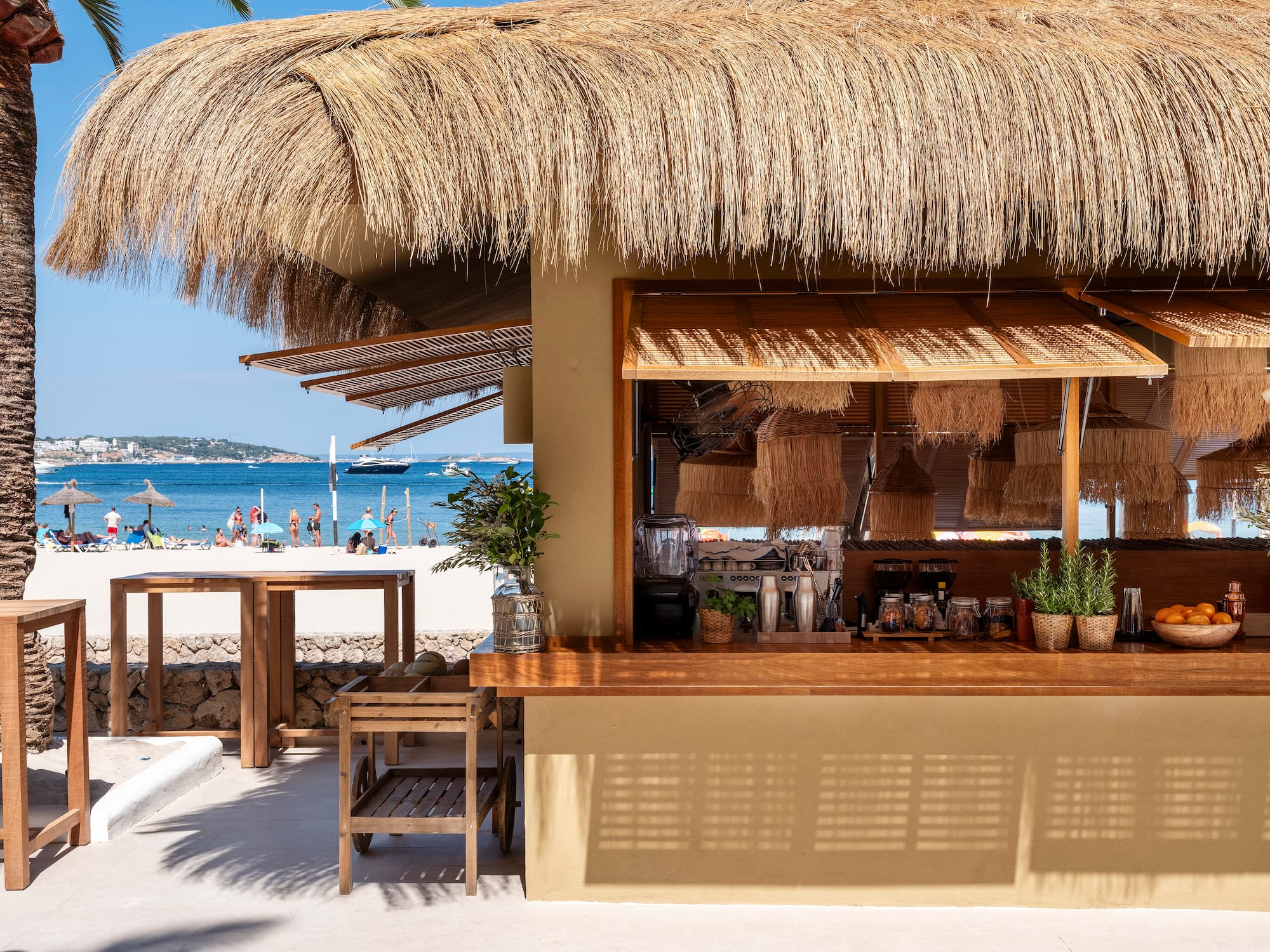 a bar with a straw roof and a beach in the background