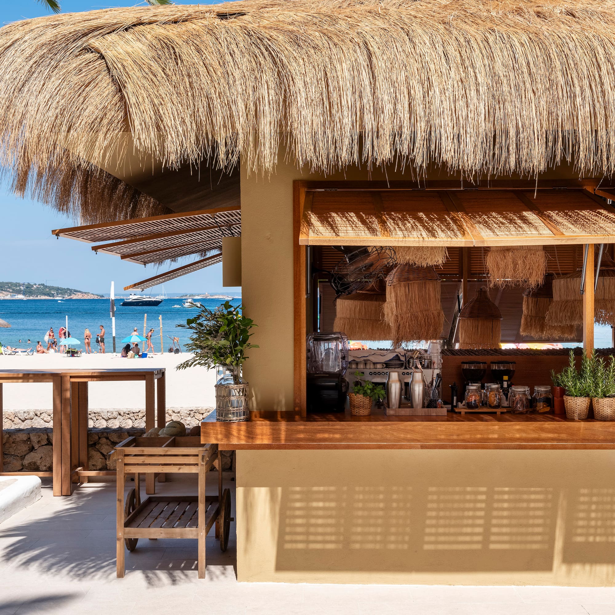 a bar with a straw roof and a beach in the background