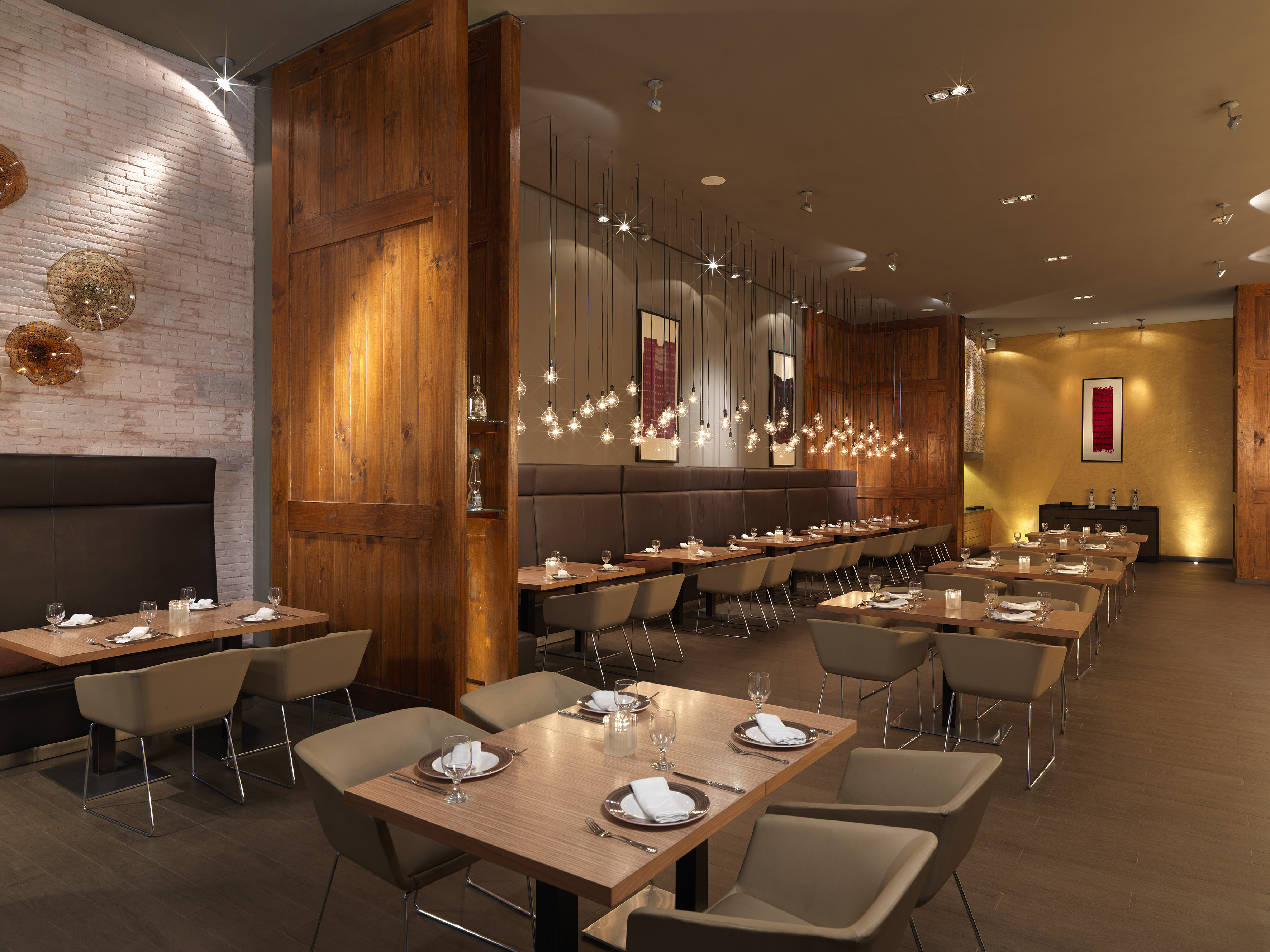 Modern restaurant dining room with warm lighting, tables, and cozy chairs.