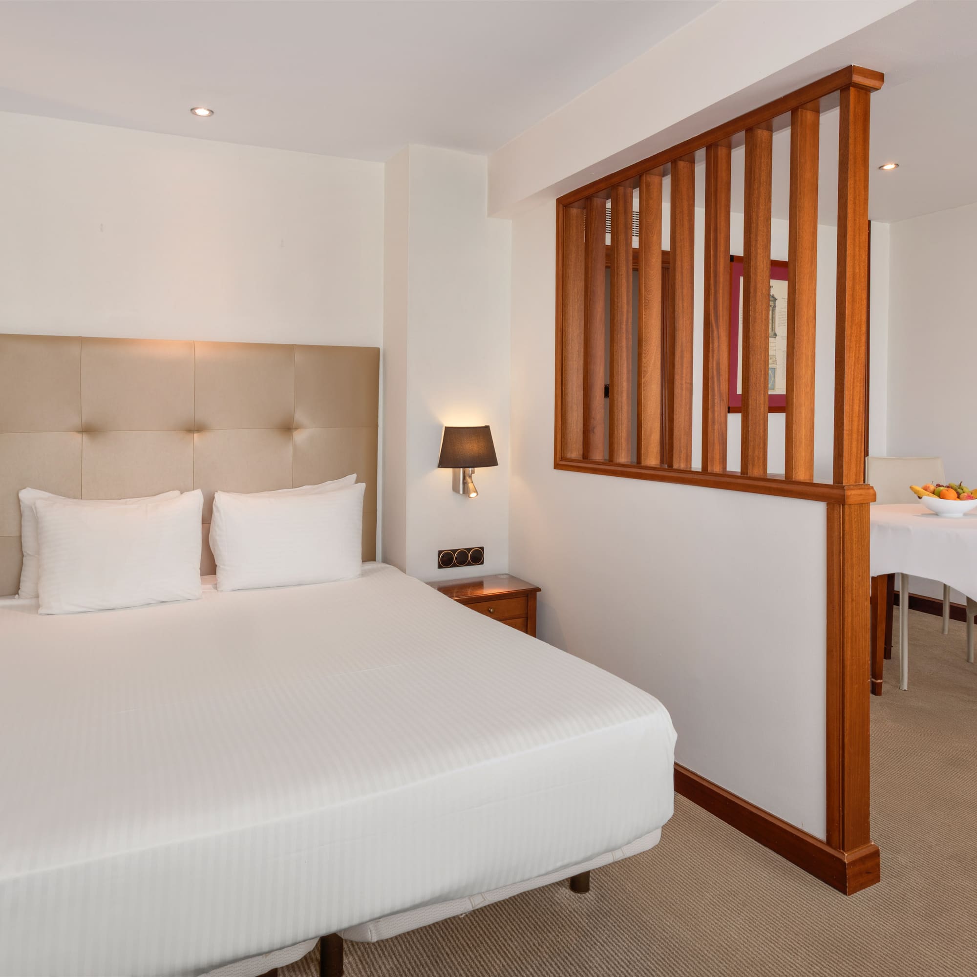 Comfortable hotel suite with queen bed and adjacent dining area.