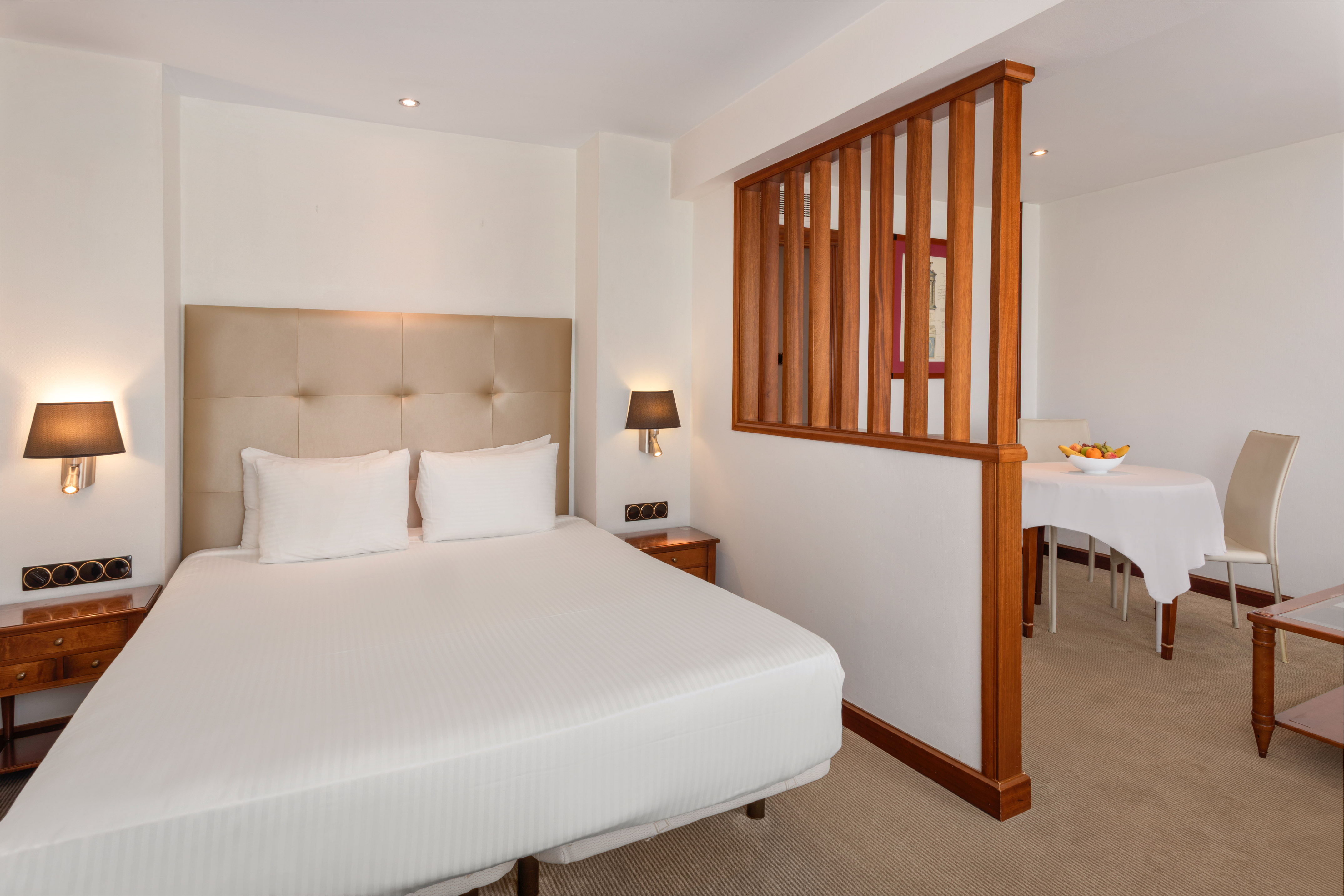 Comfortable hotel suite with queen bed and adjacent dining area.